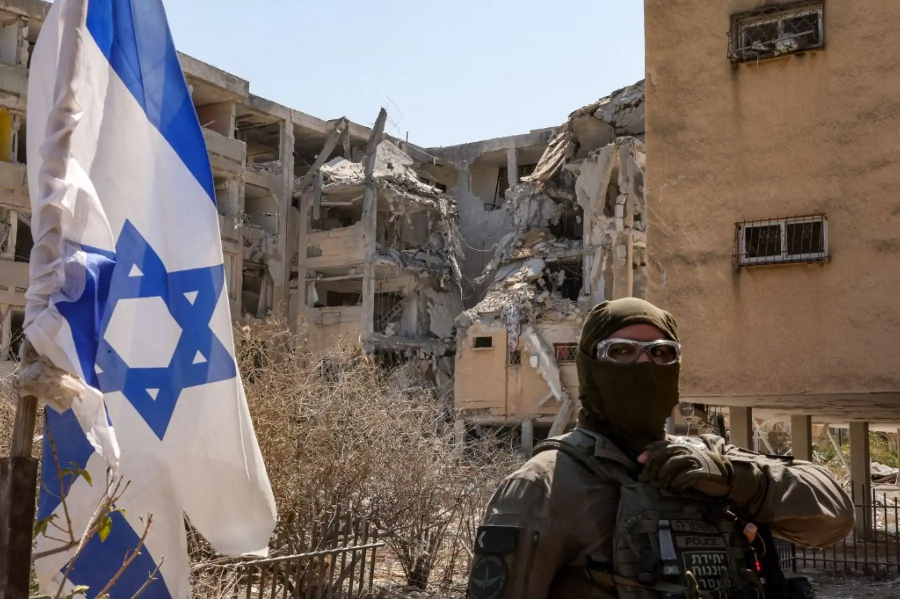 Un policía israelí enmascarado monta guardia frente a un edificio que fue alcanzado por un misil iraní en Holón, ciudad del centro de Israel. Foto: AFP