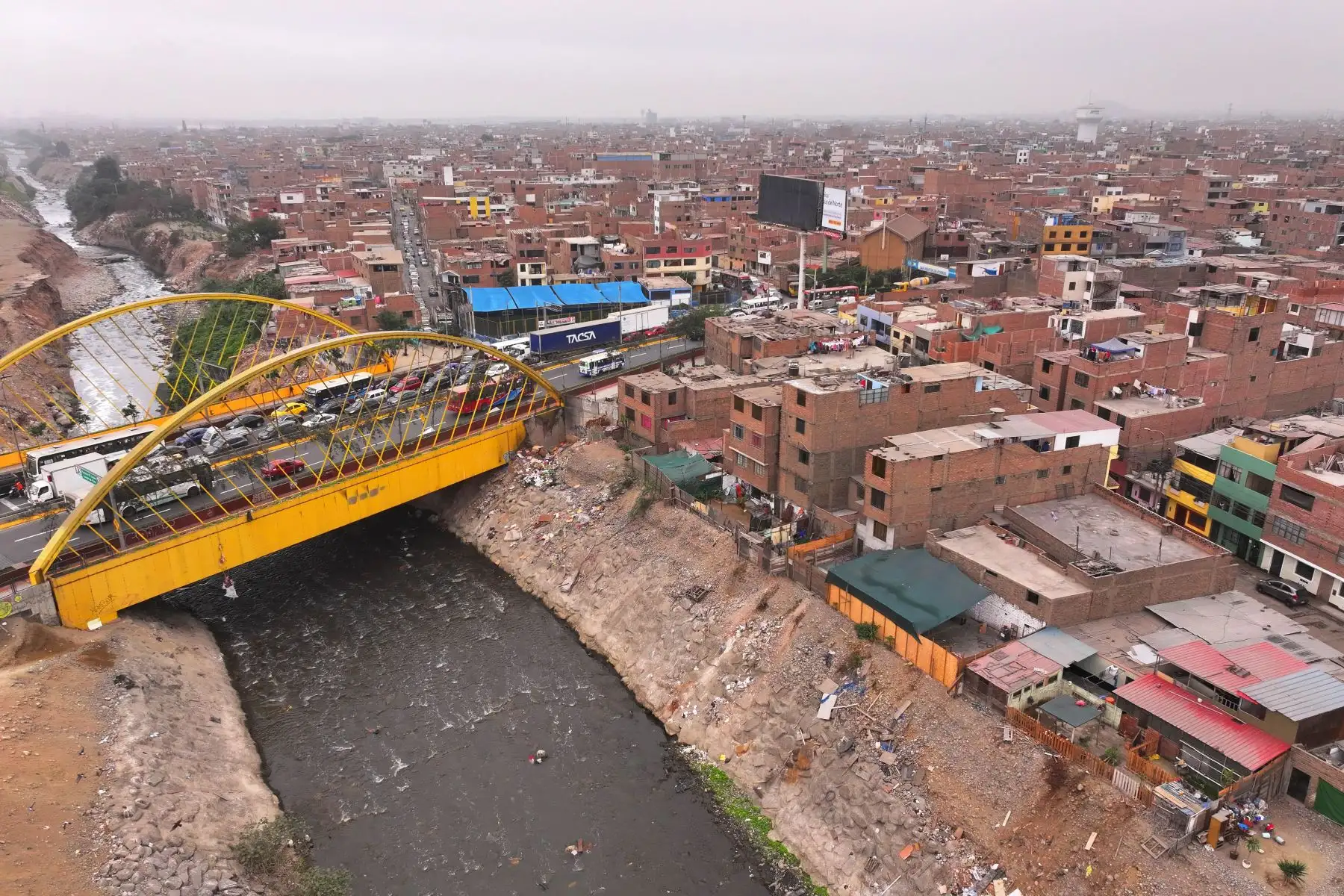 A la altura del cruce de las avenidas Morales Duárez y Universitaria en el Callao, por donde pasa el río Rímac, se observan algunas casas de material noble y precario construidas en los bordes del cause, las cuales en un eventual movimiento sísmico de gran magnitud podrían colapsar y poner en riesgo la vida de sus residentes. Foto: ANDINA/Daniel Bracamonte