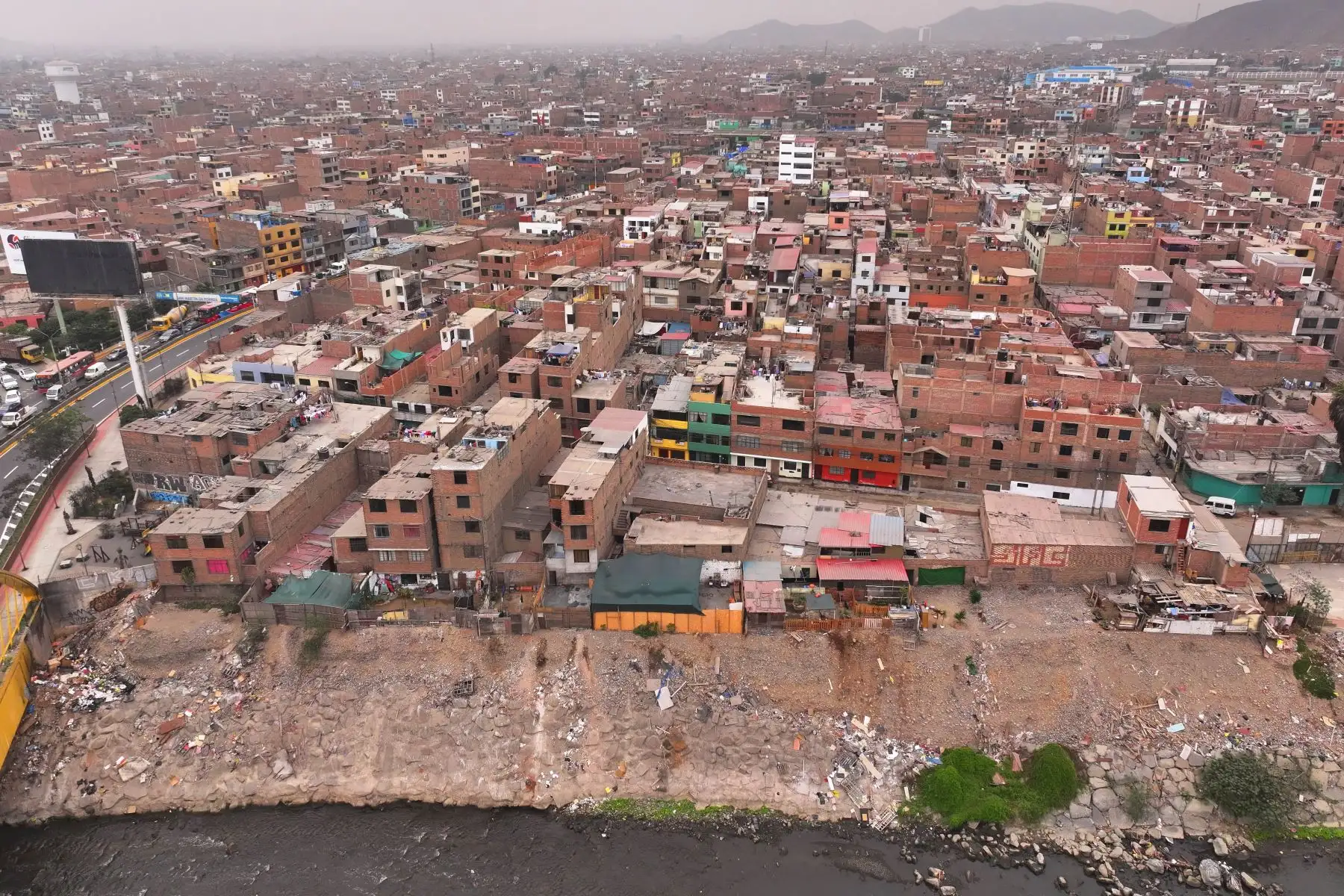 A la altura del cruce de las avenidas Morales Duárez y Universitaria en el Callao, por donde pasa el río Rímac, se observan algunas casas de material noble y precario construidas en los bordes del cause, las cuales en un eventual movimiento sísmico de gran magnitud podrían colapsar y poner en riesgo la vida de sus residentes. Foto: ANDINA/Daniel Bracamonte