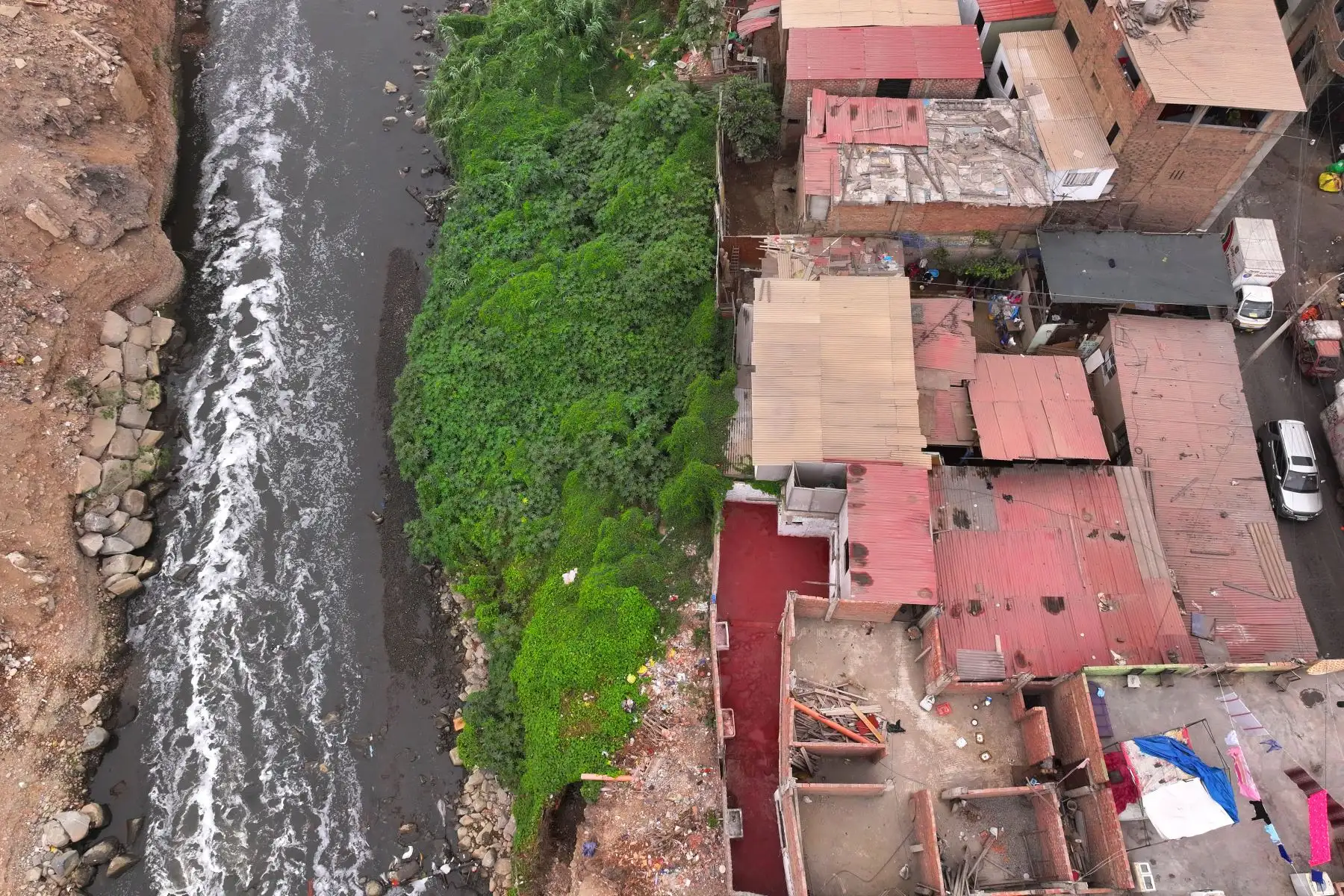 A la altura del cruce de las avenidas Morales Duárez y Universitaria en el Callao, por donde pasa el río Rímac, se observan algunas casas de material noble y precario construidas en los bordes del cause, las cuales en un eventual movimiento sísmico de gran magnitud podrían colapsar y poner en riesgo la vida de sus residentes. Foto: ANDINA/Daniel Bracamonte