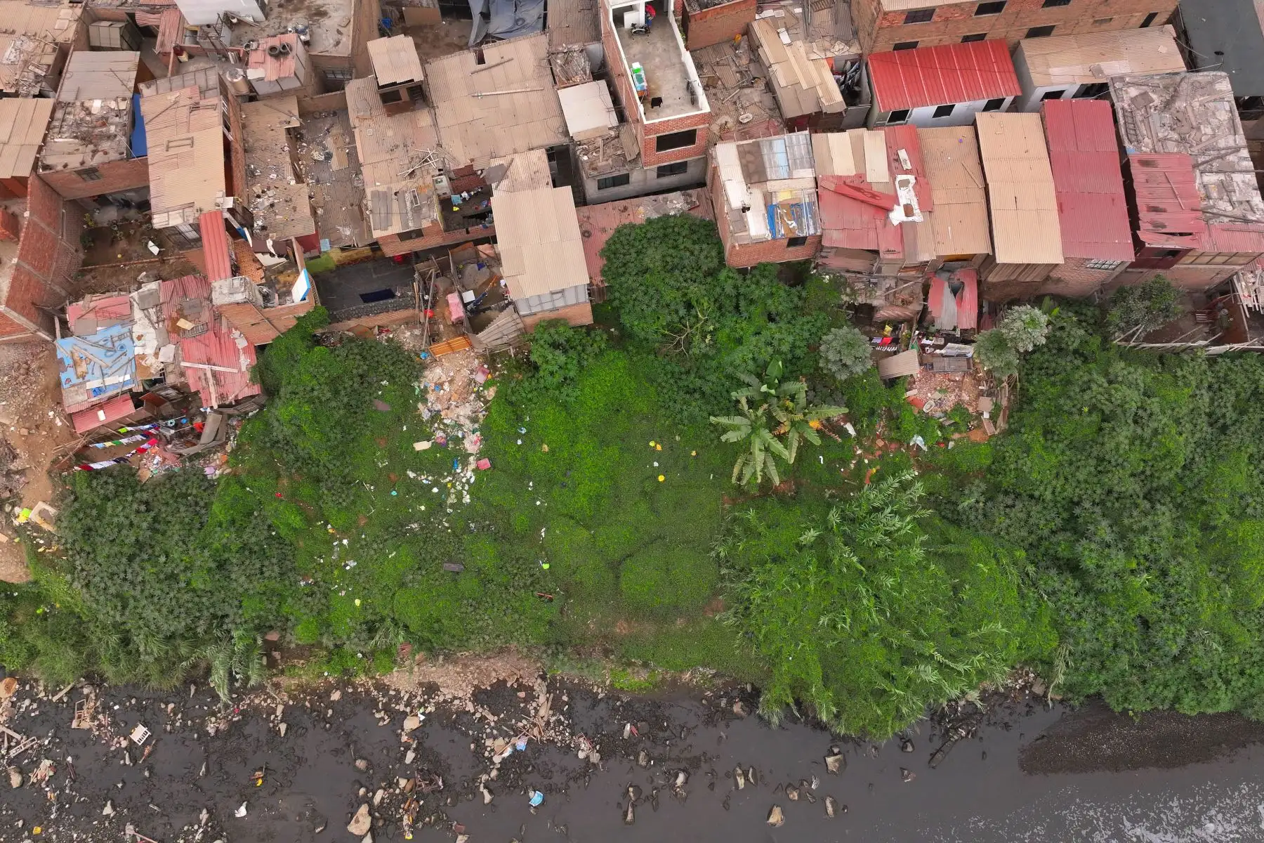 A la altura del cruce de las avenidas Morales Duárez y Universitaria en el Callao, por donde pasa el río Rímac, se observan algunas casas de material noble y precario construidas en los bordes del cause, las cuales en un eventual movimiento sísmico de gran magnitud podrían colapsar y poner en riesgo la vida de sus residentes. Foto: ANDINA/Daniel Bracamonte