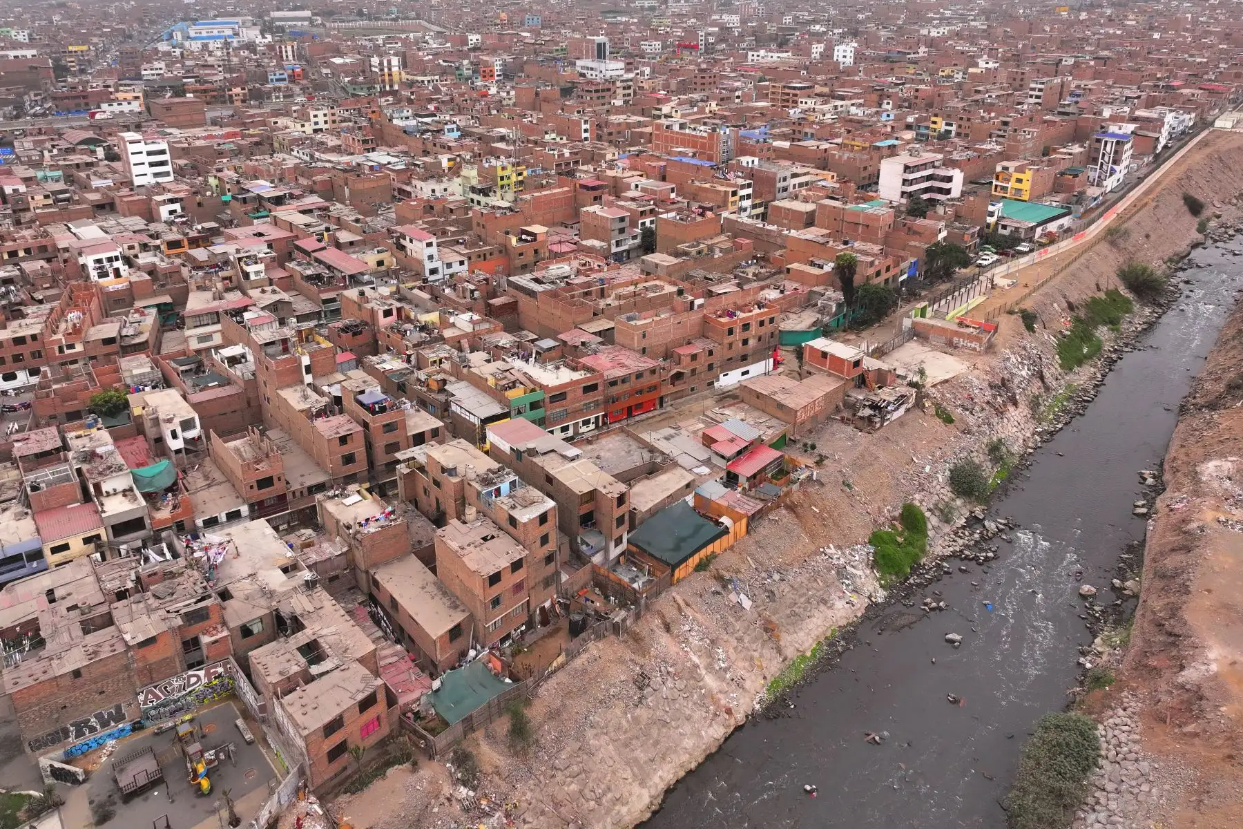 A la altura del cruce de las avenidas Morales Duárez y Universitaria en el Callao, por donde pasa el río Rímac, se observan algunas casas de material noble y precario construidas en los bordes del cause, las cuales en un eventual movimiento sísmico de gran magnitud podrían colapsar y poner en riesgo la vida de sus residentes. Foto: ANDINA/Daniel Bracamonte