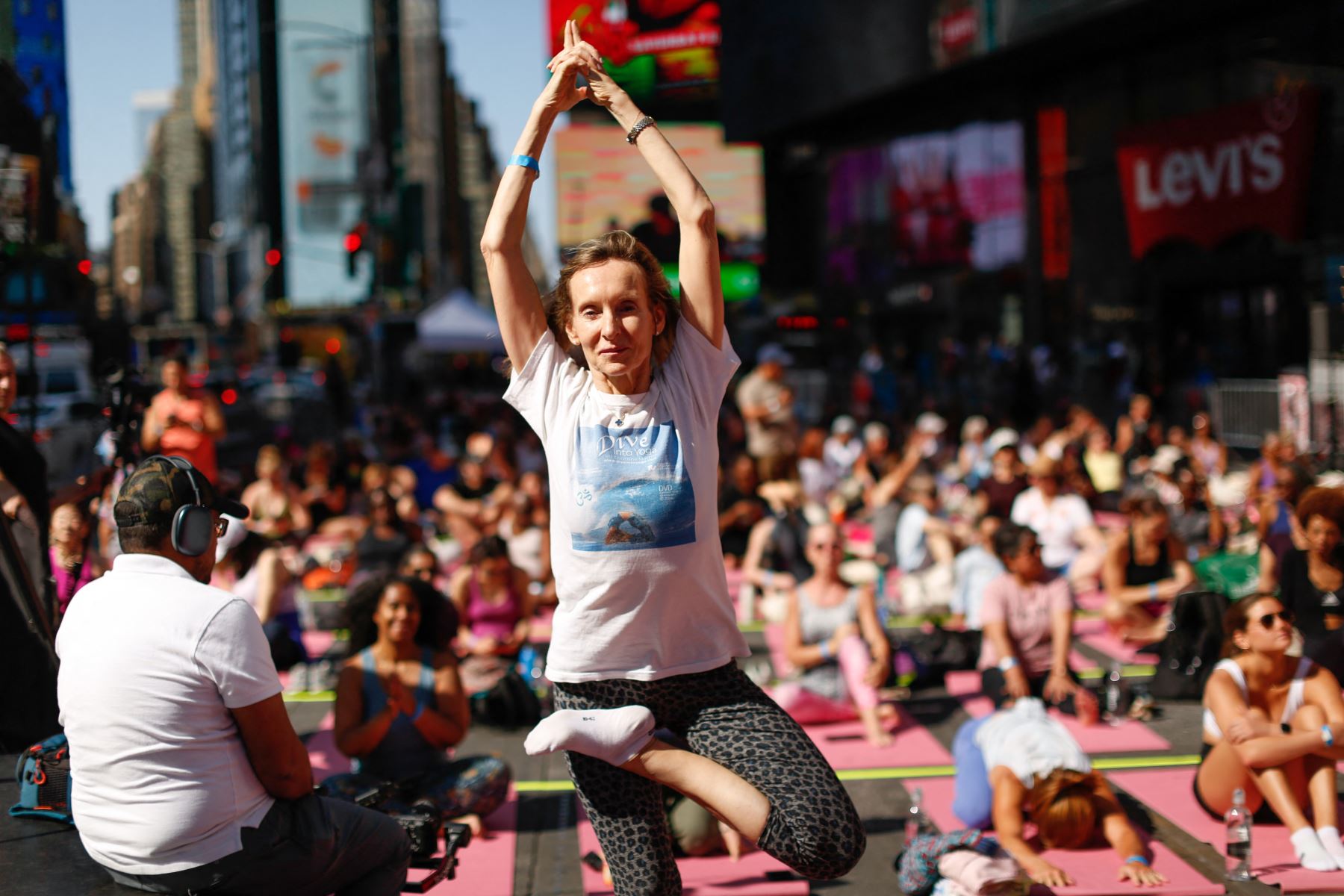 Una mujer calienta durante la 23.ª edición anual de "Solsticio en Times Square: Yoga para la Mente y la Locura" en Times Square, Nueva York. Durante los últimos veintitrés años, los organizadores han celebrado este evento de yoga durante el día más largo del año, en una de las intersecciones más transitadas del mundo, para promover la paz y la calma. AFP