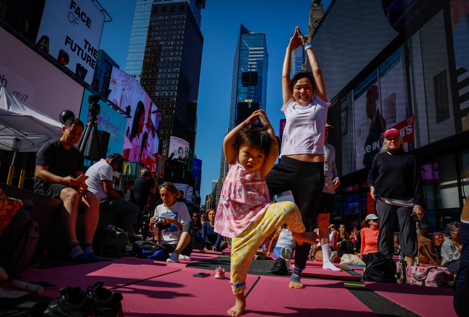 Una mujer y su hija de dos años participan en la 23.ª edición anual de "Solsticio en Times Square: Yoga para superar la locura" en Times Square, Nueva York. AFP