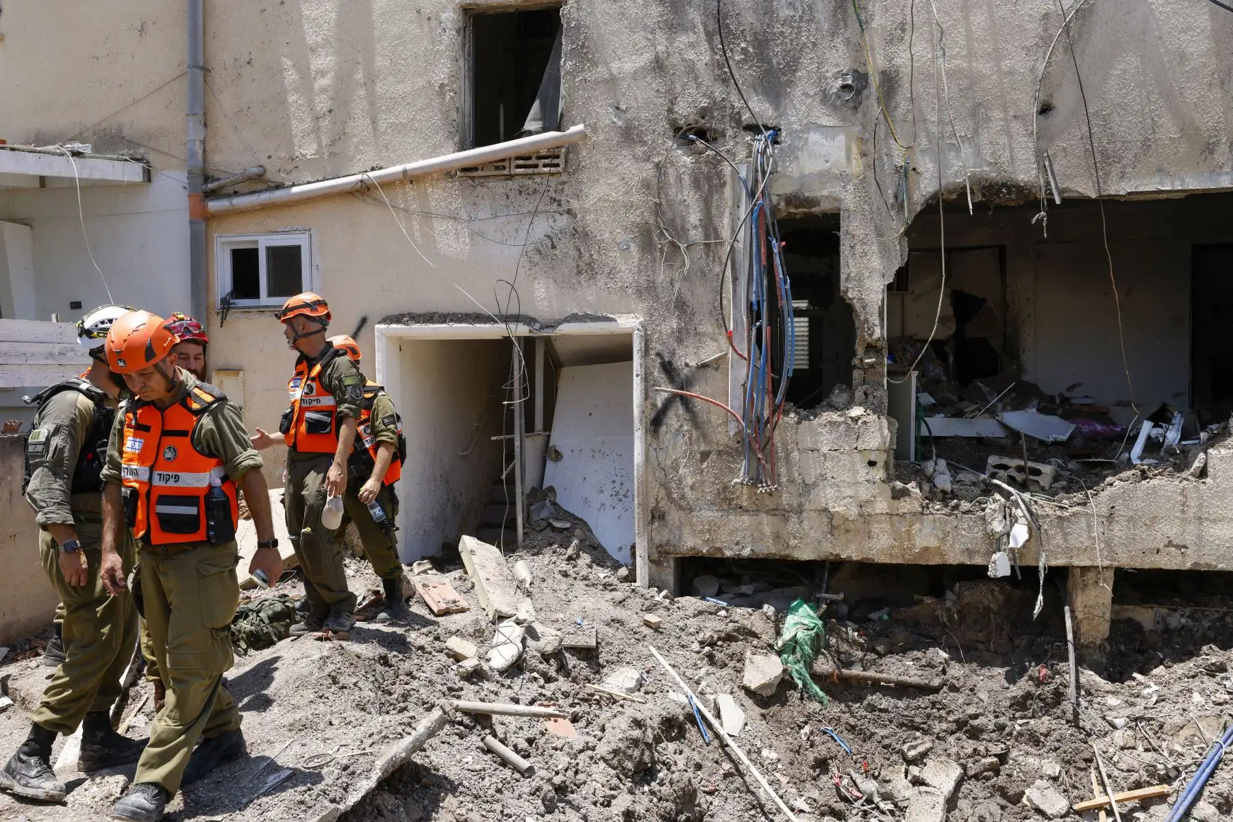 Soldados israelíes y socorristas verifican los daños causados ​​a un edificio por un ataque iraní en Beit She