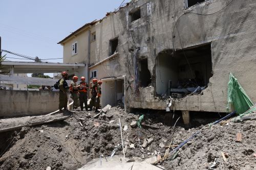 Soldados israelíes y socorristas verifican los daños causados ​​a un edificio por un ataque iraní en Beit She