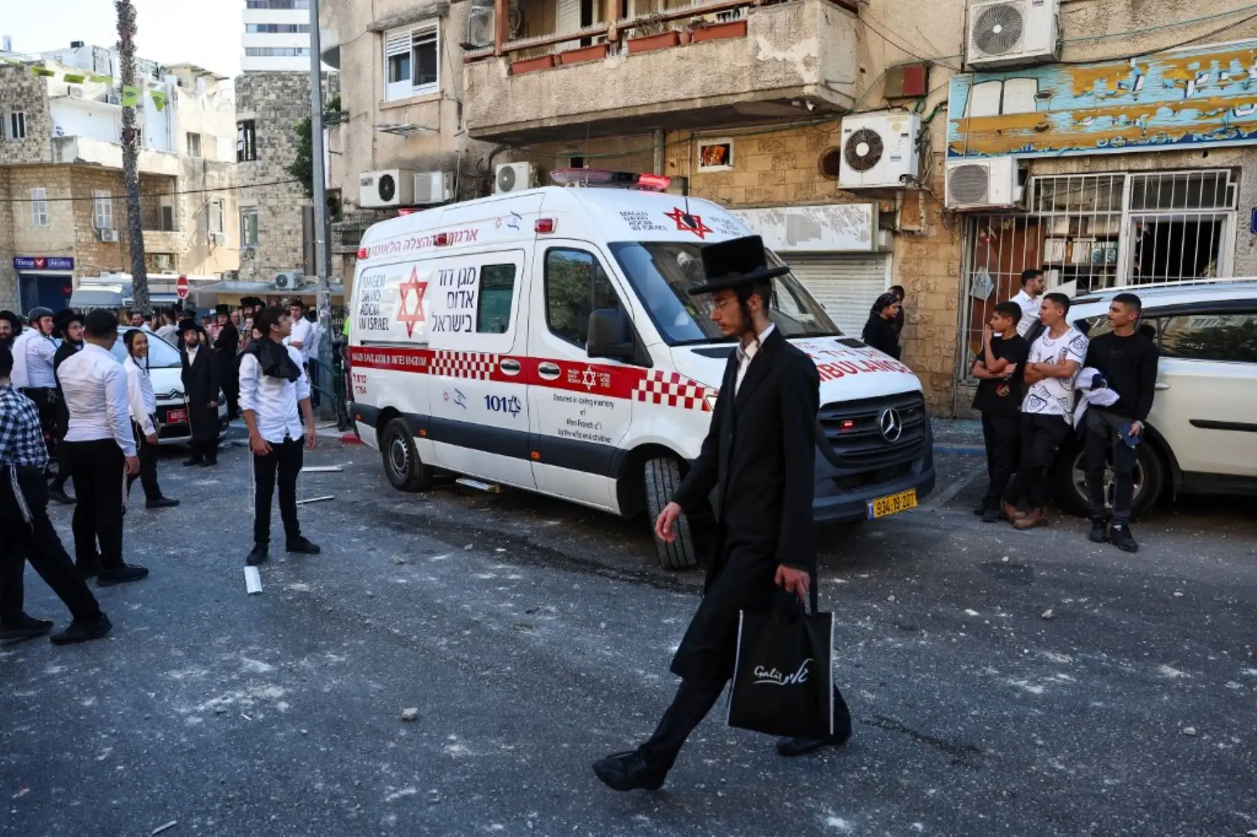 Un judío ultraortodoxo pasa junto a una ambulancia mientras la gente se congrega cerca del lugar de un ataque iraní que impactó una zona residencial en la ciudad portuaria israelí de Haifa. Foto: AFP