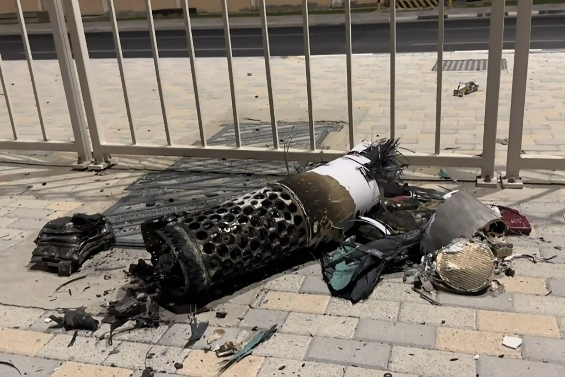 Esta captura de pantalla de AFPTV muestra los restos de un misil iraní interceptado sobre Qatar, yaciendo sobre una acera cerca de una valla el 23 de junio de 2025. Qatar declaró el 23 de junio que la situación de seguridad era "estable" tras un ataque con misiles iraníes contra una base estadounidense en su territorio. Foto: AFP
