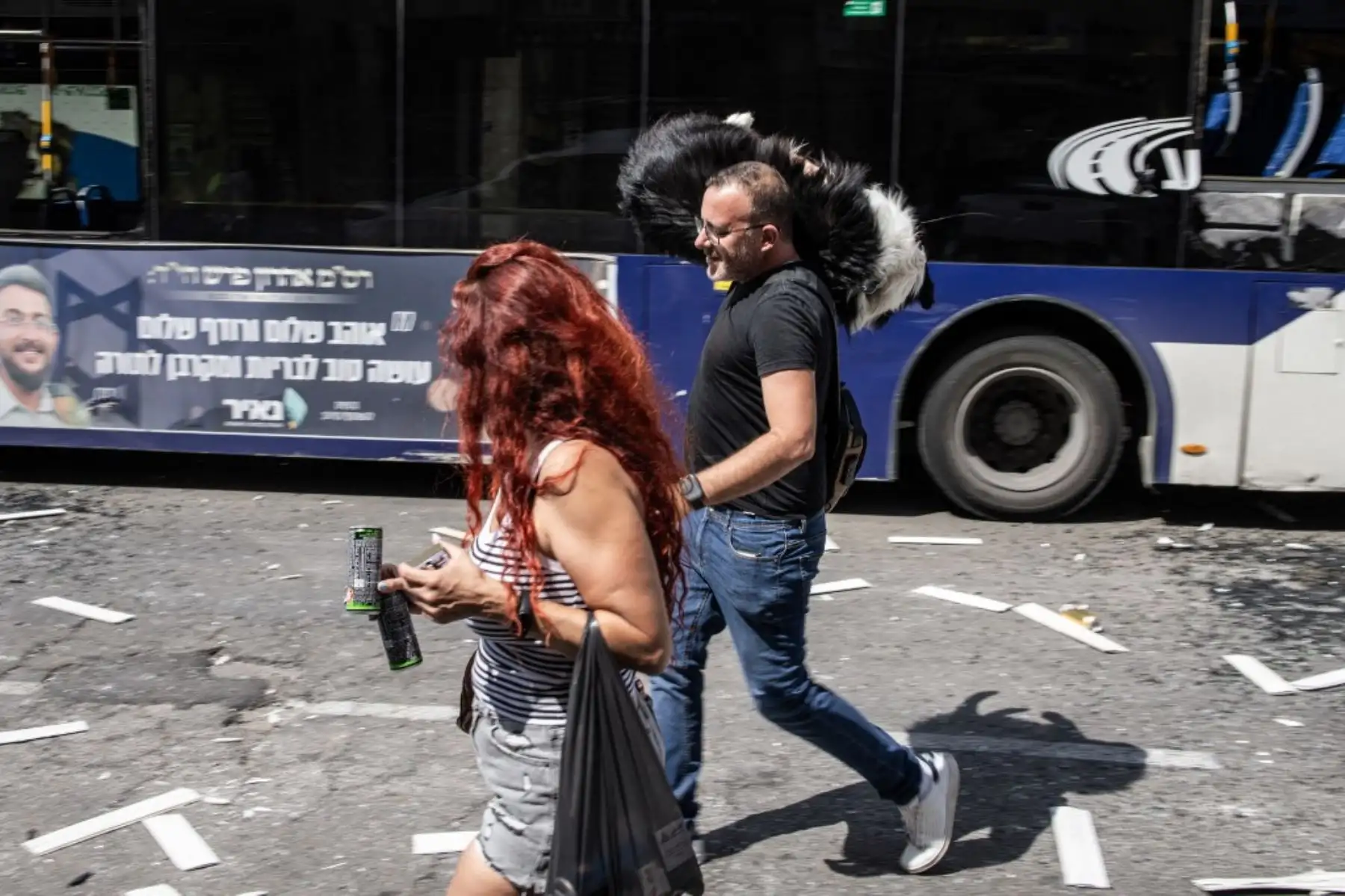 Un hombre con un perro al hombro camina con una mujer sobre escombros en una zona impactada por un misil iraní en Beersheba, al sur de Israel. Foto: AFP