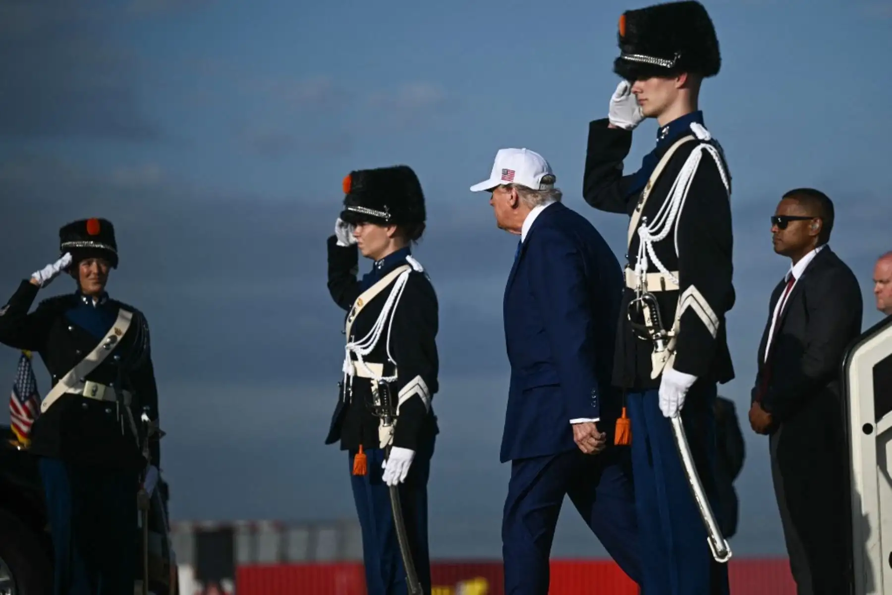 Trump, que llegó vestido con un traje y corbata azul y con una gorra blanca con las letras USA y la bandera estadounidense, ha llegado solo a Países Bajos, sin la compañía de Melania Trump. Foto: AFP
