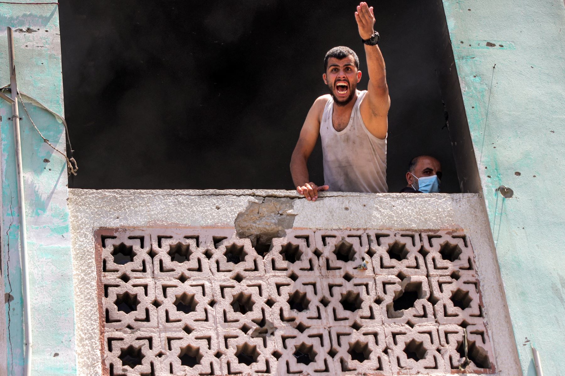 Un hombre grita a los demás que están abajo mientras los socorristas intentan extinguir un incendio tras un ataque israelí en la escuela Osama bin Zaid de la UNRWA en el distrito de Saftawi, en el oeste de Jabalia, en el norte de la Franja de Gaza. AFP