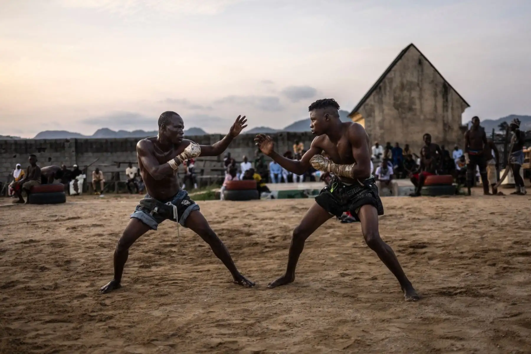 En Abuya, Nigeria, el dambe, una lucha tradicional con raíces en la etnia hausa, vive un resurgimiento gracias a su profesionalización. Los luchadores, protegidos con amuletos y guiados por oraciones, participan en combates intensos que ahora se transmiten globalmente. Con apoyo del WAFC y plataformas como DAZN, el dambe atrae tanto a nuevos talentos como a espectadores internacionales, convirtiéndose en un símbolo cultural que mezcla tradición, fe y deporte de contacto. Foto: AFP