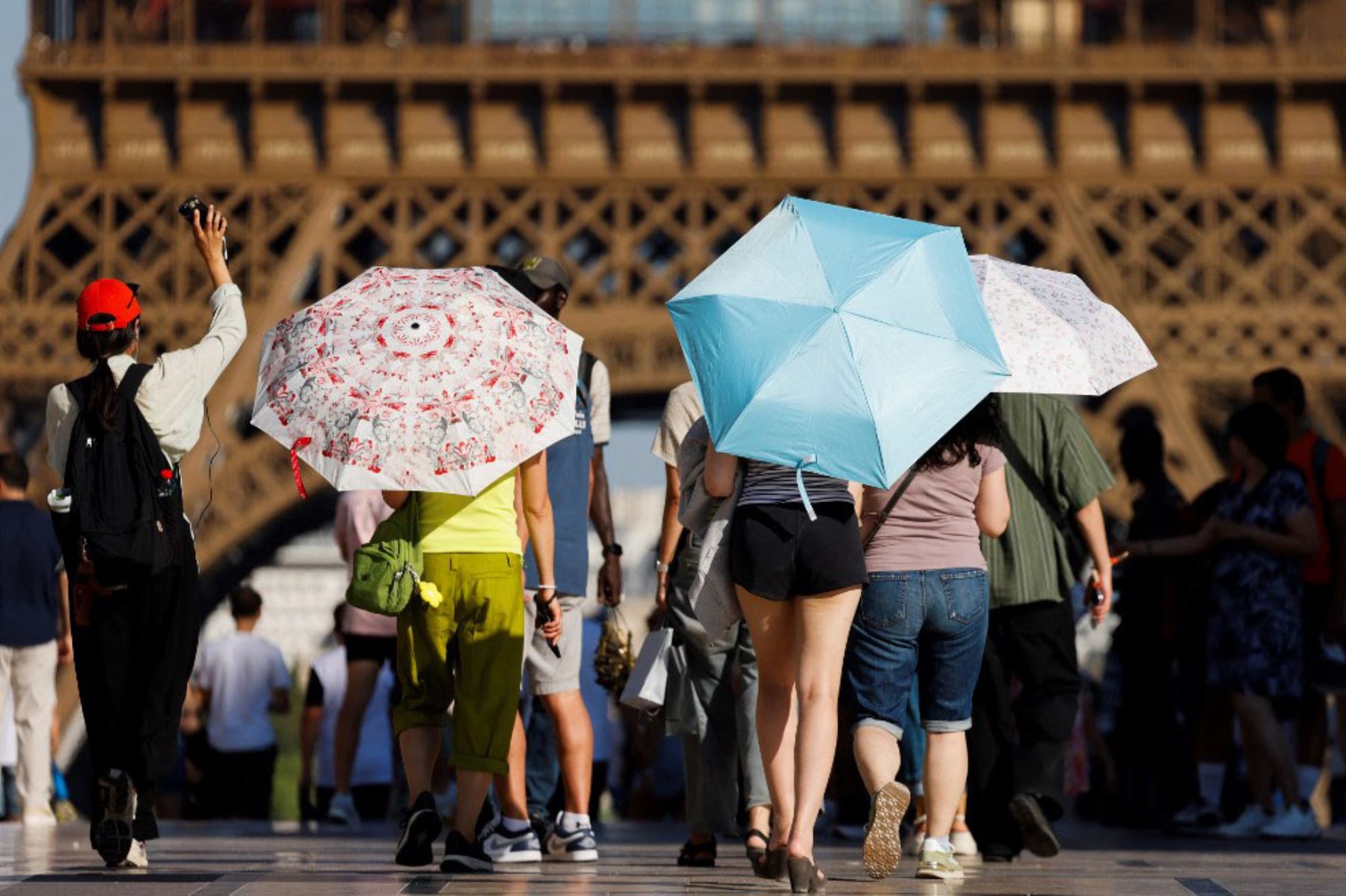 Los turistas sostienen paraguas para protegerse del sol durante una ola de calor en la plaza Trocadero, cerca de la Torre Eiffel, en París, Francia, el 30 de junio de 2025. Las autoridades francesas pusieron a París en alerta roja por calor extremo. Foto: AFP