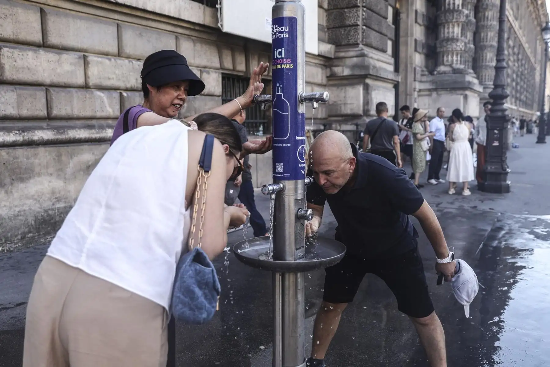 Personas intentan refrescarse en un punto de agua instalado por el Ayuntamiento de París cerca de Louvre durante un caluroso día en Francia, el 30 de junio de 2025. A partir del 1 de julio, París y otros 16 departamentos estarán en alerta roja por ola de calor extrema. Foto: EFE