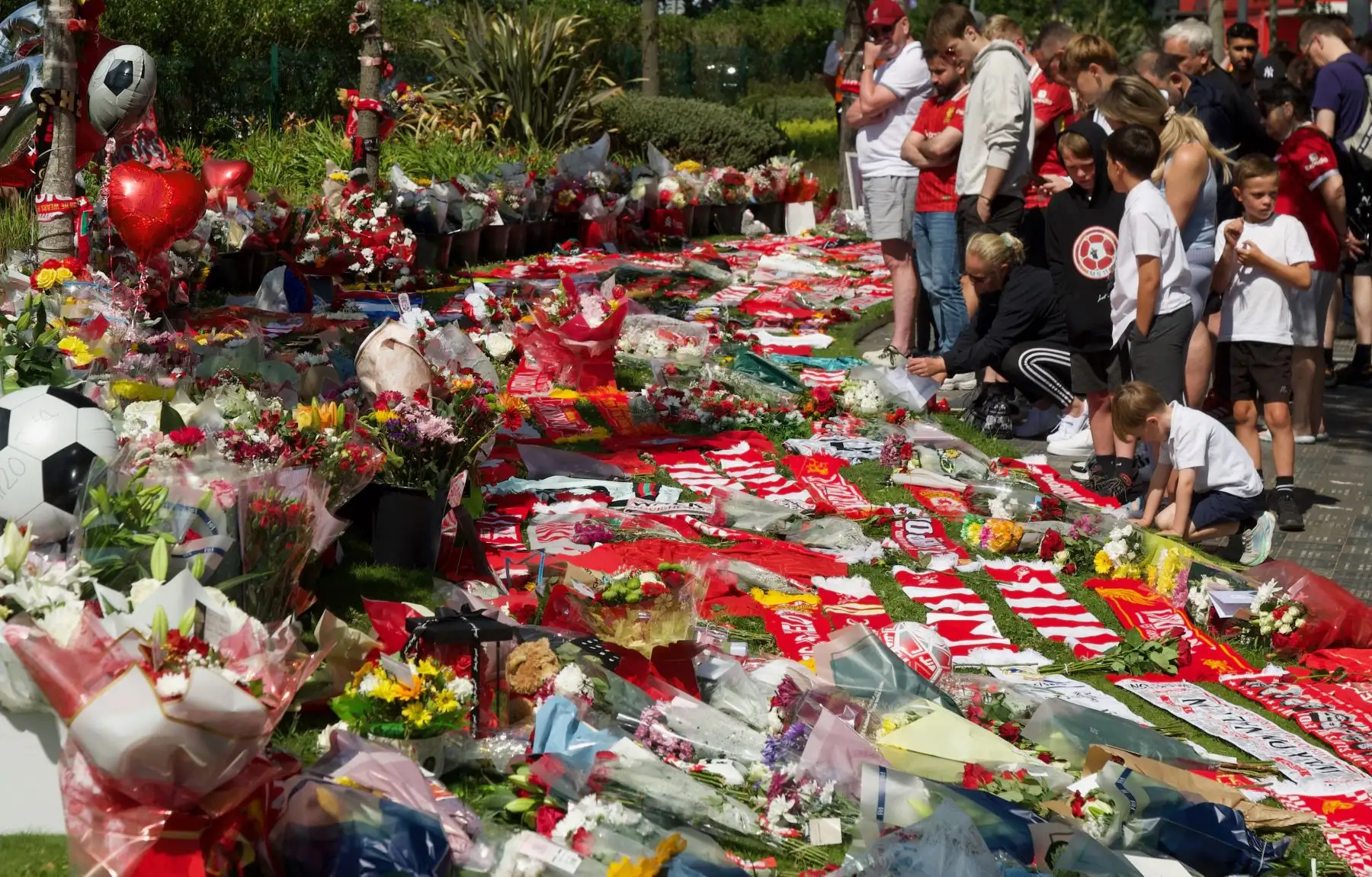 Personas que apoyan al delantero portugués Diogo Jota depositan flores en un monumento erigido cerca del estadio de fútbol de Anfield en Liverpool. AFP