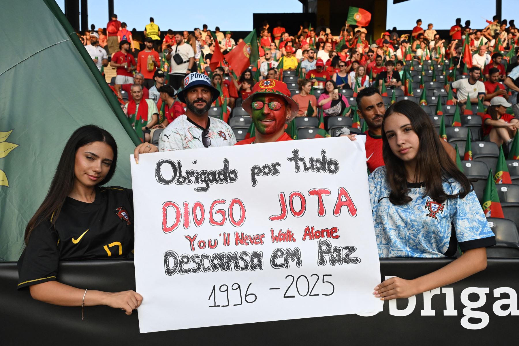 Los aficionados sostienen pancartas mientras rinden homenaje al delantero portugués del Liverpool Diogo Jota, que falleció hoy en un accidente automovilístico junto con su hermano en España, antes del partido de fútbol del Grupo B de la Eurocopa Femenina de la UEFA 2025 . AFP