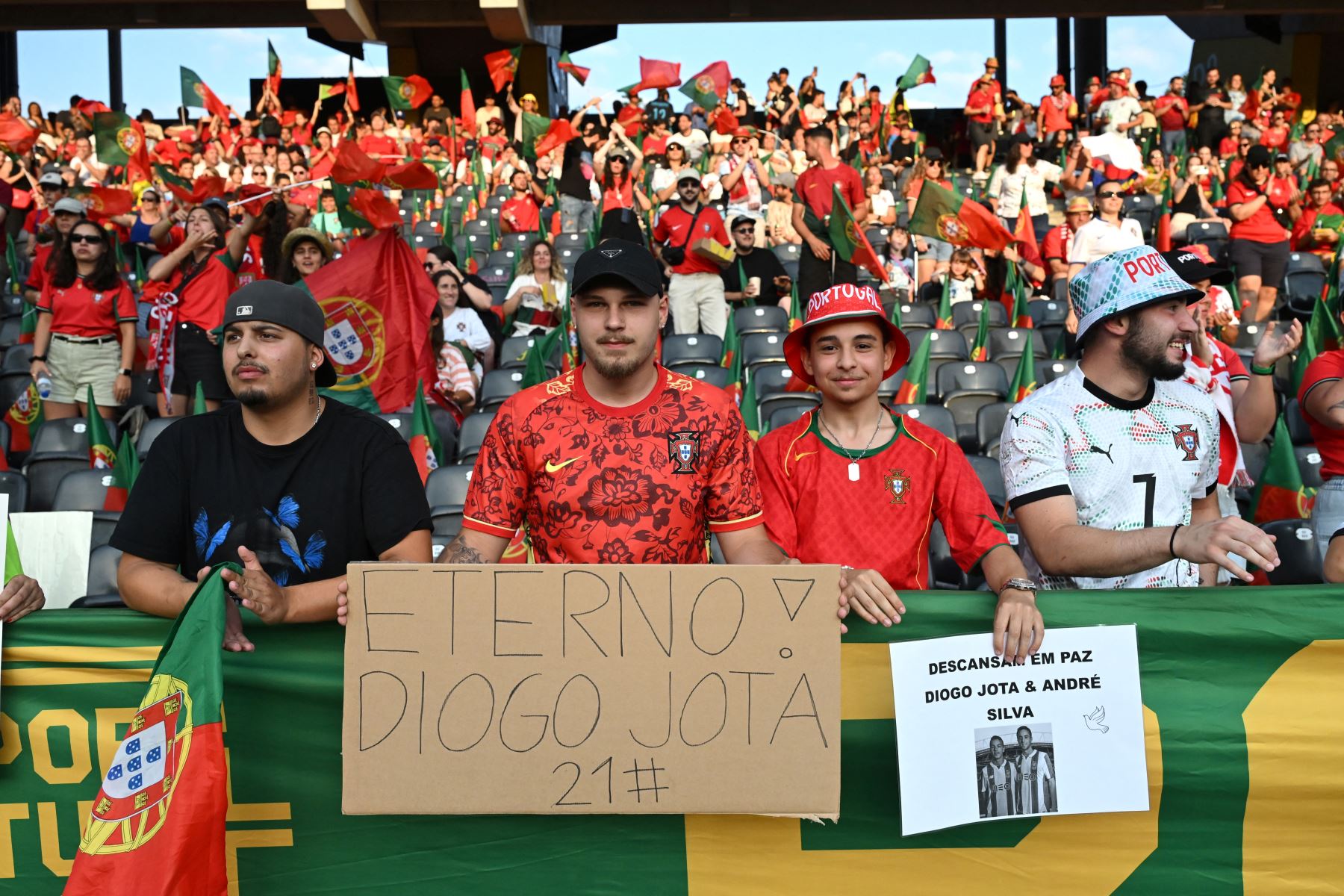 Los aficionados sostienen pancartas mientras rinden homenaje al delantero portugués del Liverpool Diogo Jota, que falleció hoy en un accidente automovilístico junto con su hermano en España, antes del partido de fútbol del Grupo B de la Eurocopa Femenina de la UEFA 2025 . AFP