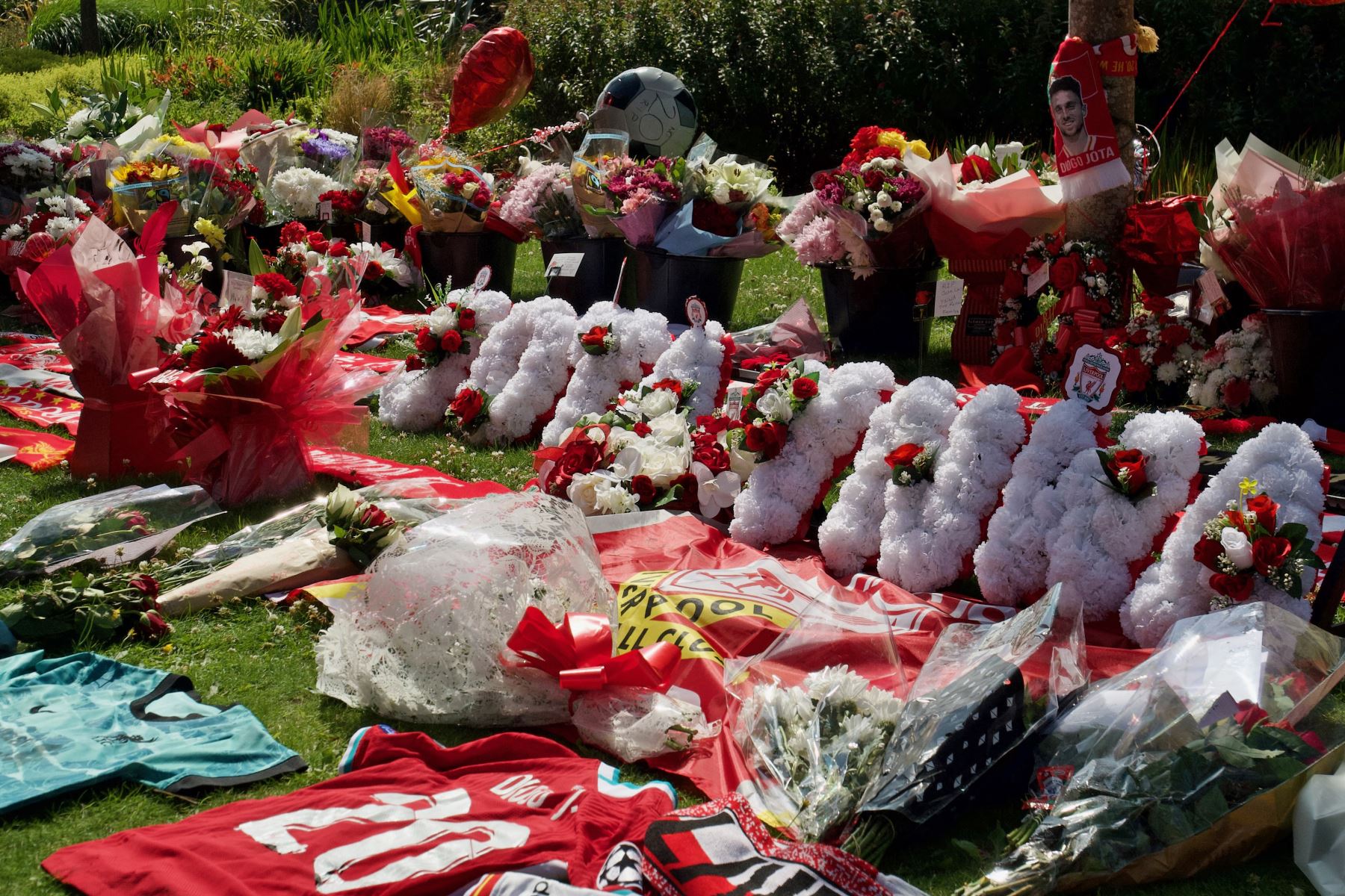 Camisetas y bufandas del Liverpool junto a flores depositadas en un monumento conmemorativo erigido cerca del estadio de fútbol de Anfield en honor al delantero portugués Diogo Jota, en Liverpool. AFP