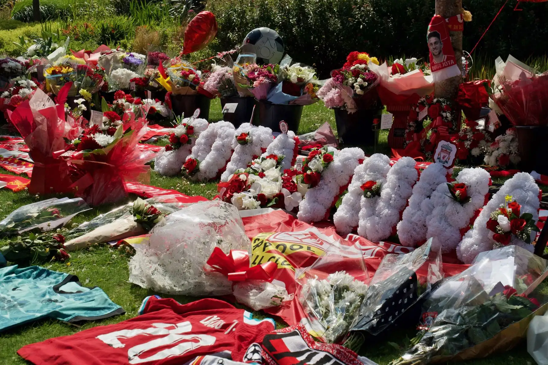 Camisetas y bufandas del Liverpool junto a flores depositadas en un monumento conmemorativo erigido cerca del estadio de fútbol de Anfield en honor al delantero portugués Diogo Jota, en Liverpool. AFP