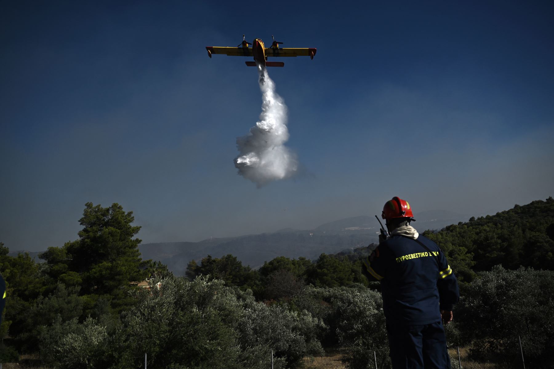 Un avión arroja agua sobre un incendio forestal que se desató en Pikermi, a unos 30 kilómetros al este de Atenas. AFP