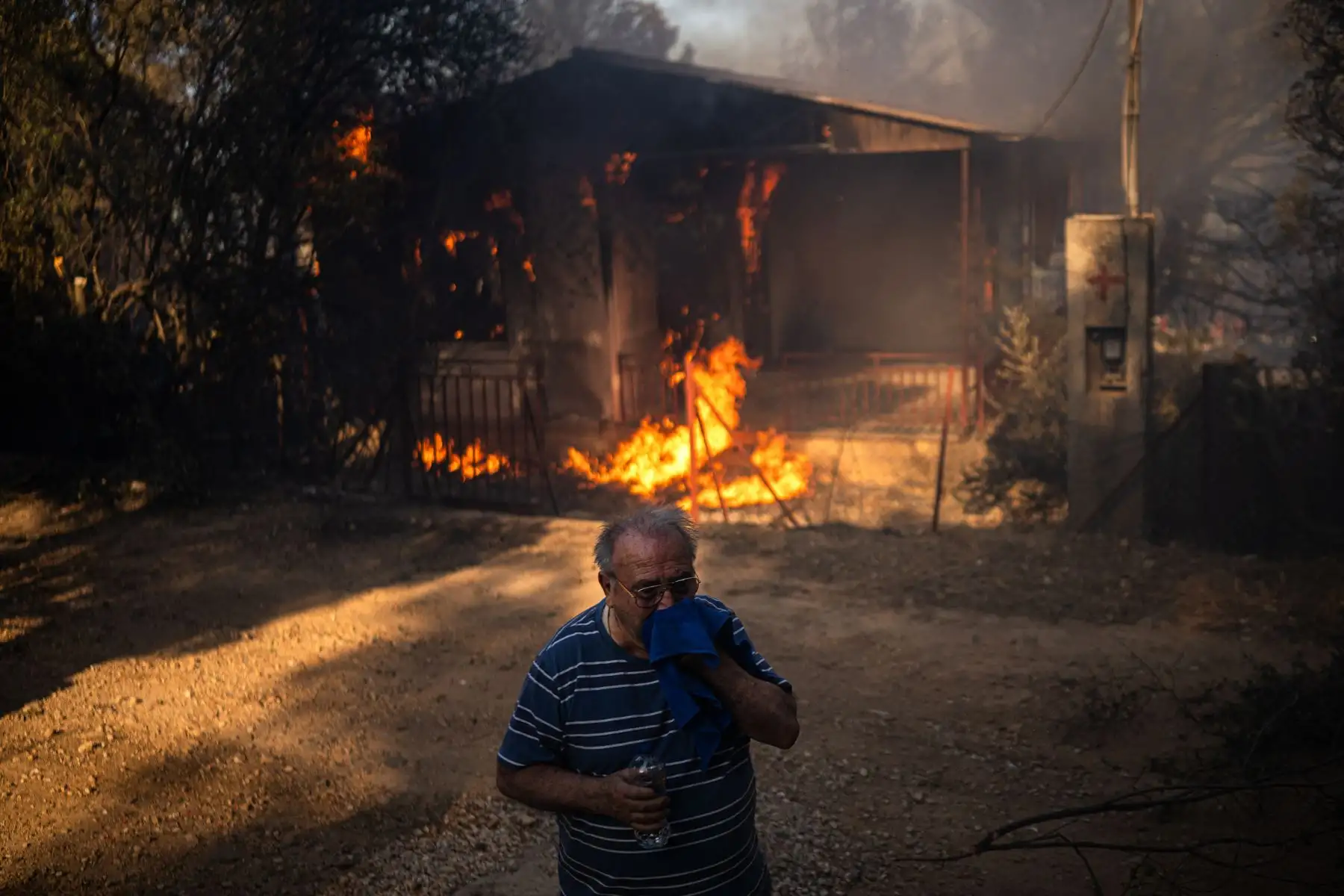 Un hombre se encuentra frente a una casa en llamas durante un incendio forestal en Pikermi, a unos 30 kilómetros al este de Atenas. AFP