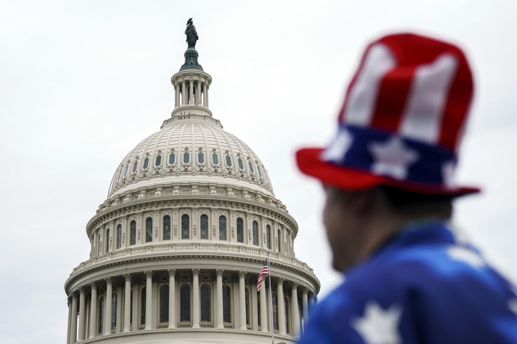 Un miembro del público vestido con un disfraz con la bandera de Estados Unidos se encuentra frente al Capitolio de Estados Unidos en Washington, D.C. AFP