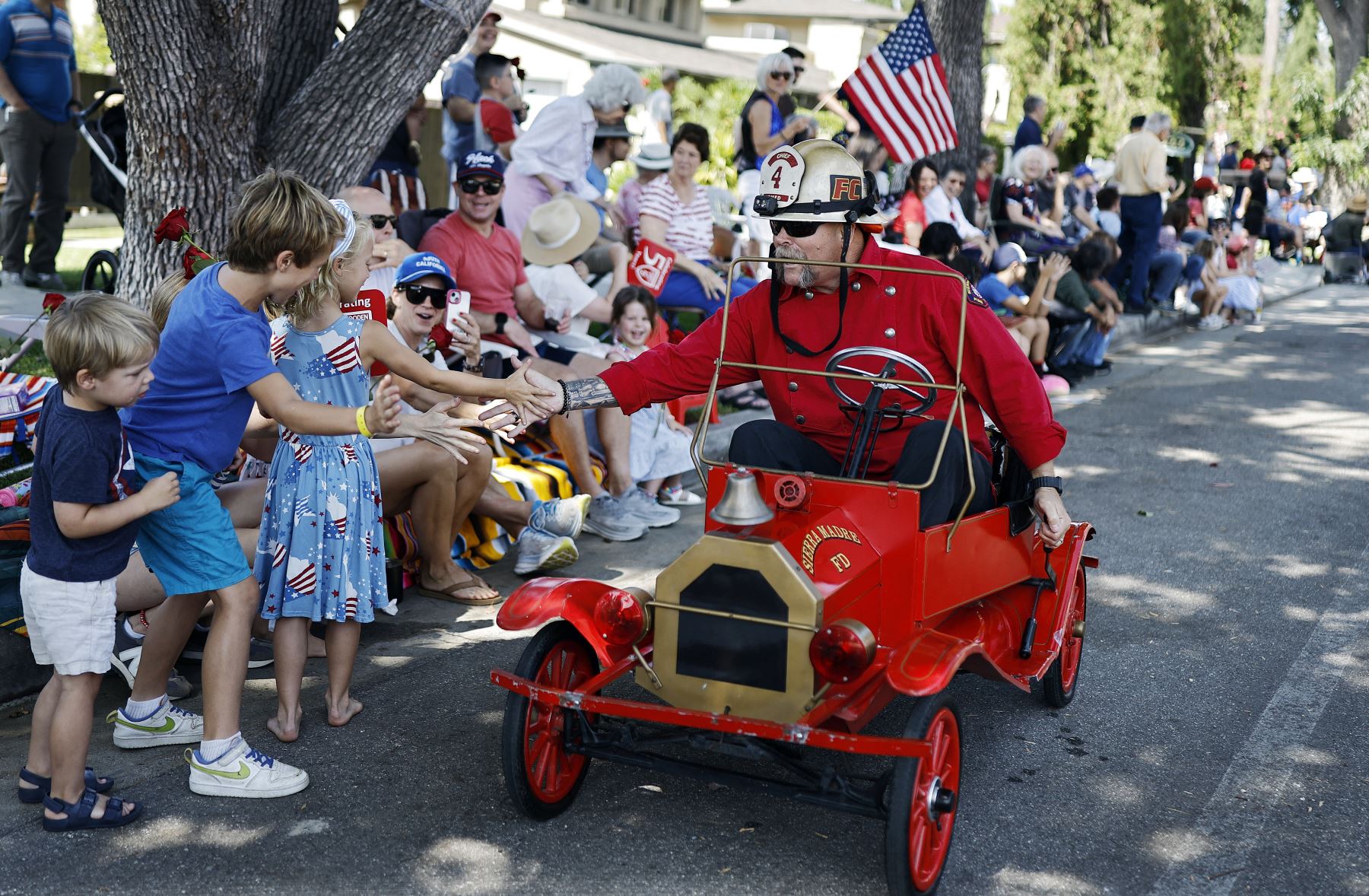 El jefe de bomberos de Sierra Madre, Brent Bartlett, saluda a los jóvenes durante el desfile del Día de la Independencia de Sierra Madre, no lejos de la zona quemada por el incendio Eaton, el 4 de julio de 2025 en Sierra Madre, California. AFP