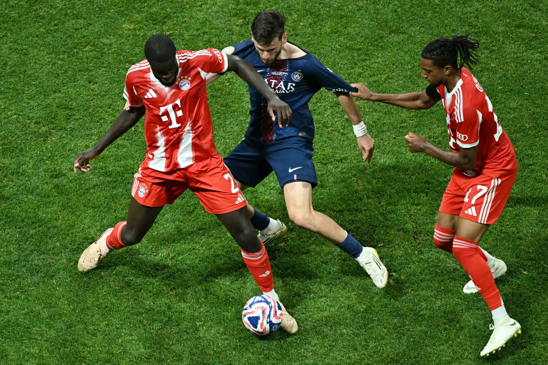 El defensa portugués del Bayern Múnich, Raphael Guerreiro, y el mediocampista francés Michael Olise luchan por el balón con el mediocampista español del Paris Saint-Germain, Fabian Ruiz, durante el partido de cuartos de final de la Copa Mundial de Clubes de la FIFA 2025 entre el Paris Saint-Germain de Francia y el Bayern Múnich de Alemania. Foto: ANDINA/AFP
