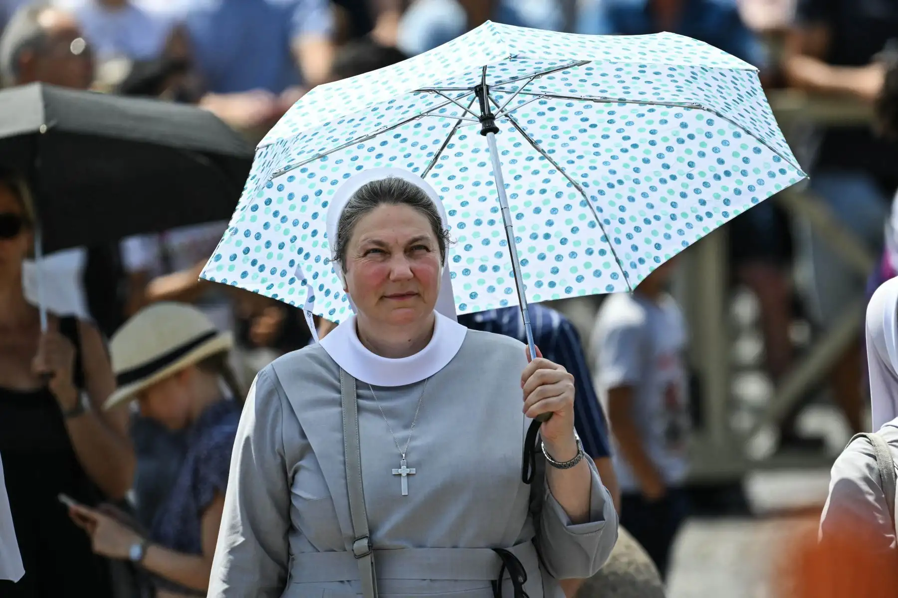 Una monja sostiene un paraguas para protegerse del sol en la plaza de San Pedro durante el rezo del Ángelus en el Vaticano. Foto: ANDINA/AFP