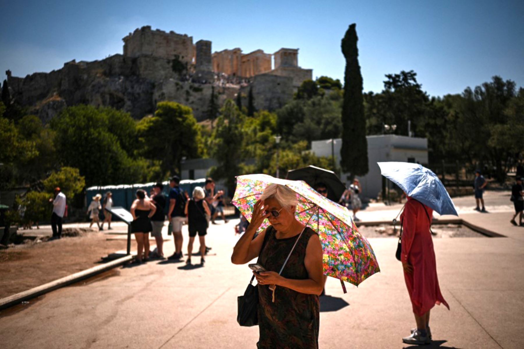 Turistas pasan junto a un contenedor de basura repleto de botellas de plástico cerca de la colina de la Acrópolis en Atenas . El principal monumento arqueológico de Grecia, la Acrópolis, estuvo parcialmente cerrado como parte de las medidas de emergencia para proteger a los visitantes y trabajadores de todo el país durante una ola de calor de cuatro días. 
Foto: AFP