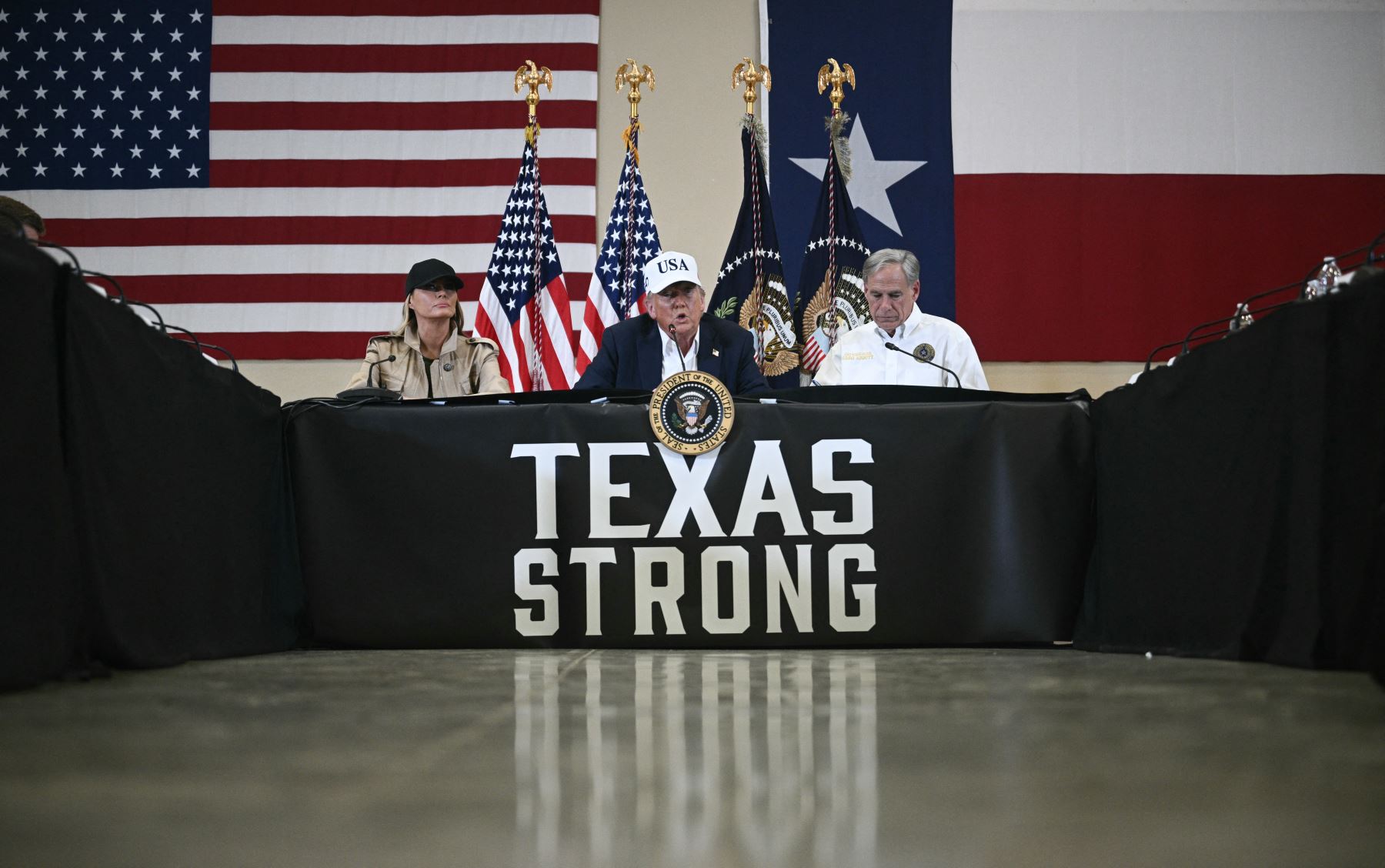 El presidente de Estados Unidos, Donald Trump, y la primera dama, Melania Trump, se sientan con el gobernador de Texas, Greg Abbott , mientras asisten a una mesa redonda con funcionarios locales y socorristas en el Happy State Bank Expo Hall en Kerrville, Texas. AFP