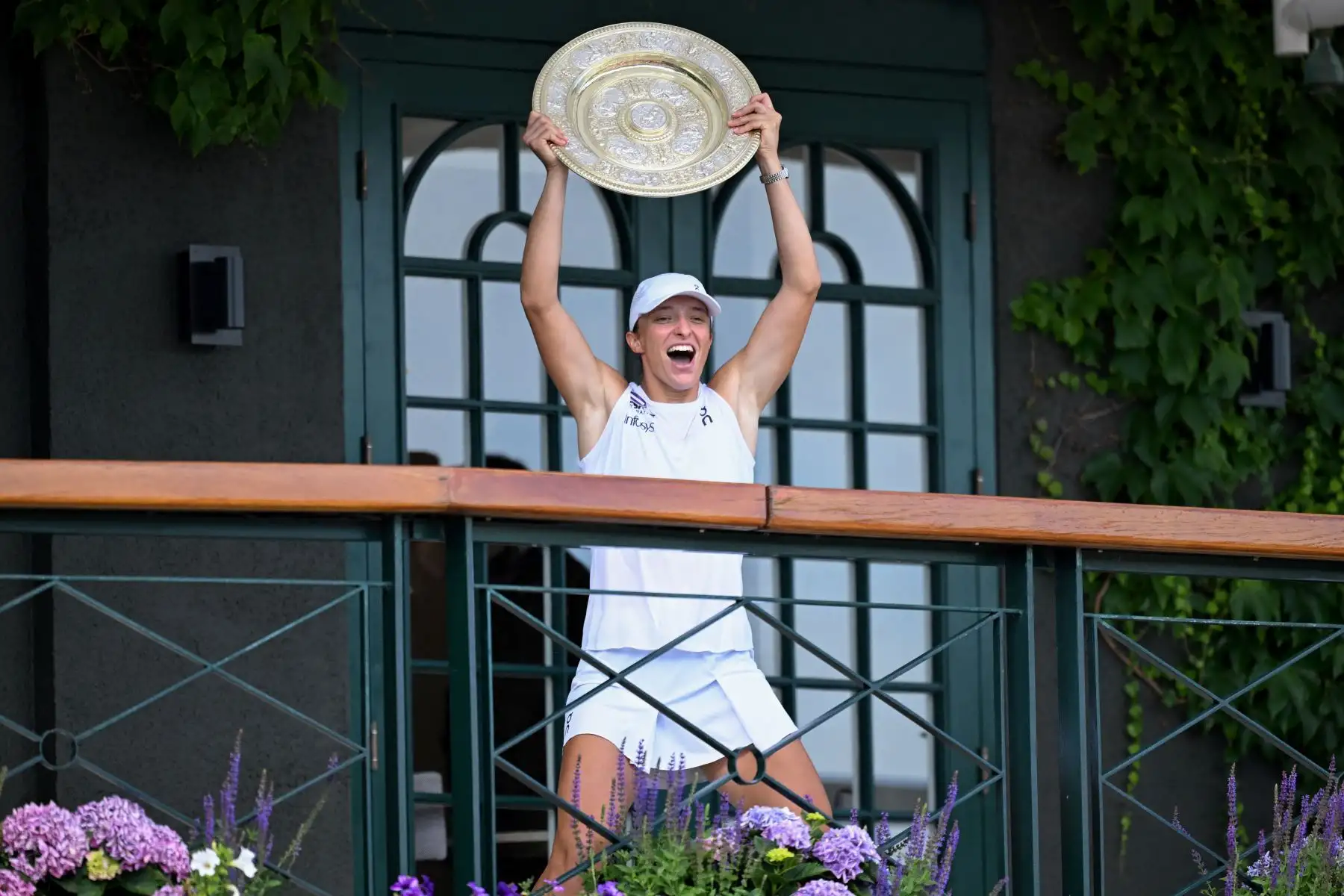 La polaca Iga Swiatek celebra con el trofeo de ganadora, el Venus Rosewater Dish, mientras lo muestra a la multitud desde el balcón de la cancha central después de ganar su partido final de tenis individual femenino contra la jugadora estadounidense Amanda Anisimova en el decimotercer día del Campeonato de Wimbledon 2025. al suroeste de Londres. Foto: ANDINA/AFP