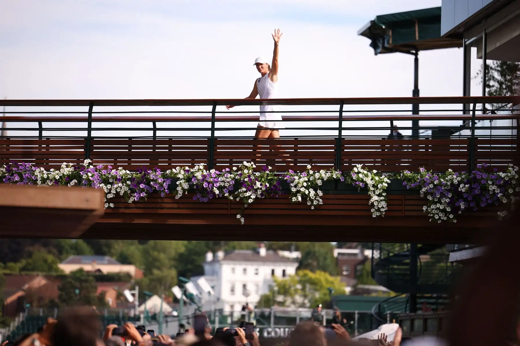La ganadora polaca Iga Swiatek saluda a la multitud mientras cruza el puente al final de su partido de tenis individual femenino contra la jugadora estadounidense Amanda Anisimova en el decimotercer día del Campeonato de Wimbledon 2025. Foto: ANDINA/AFP