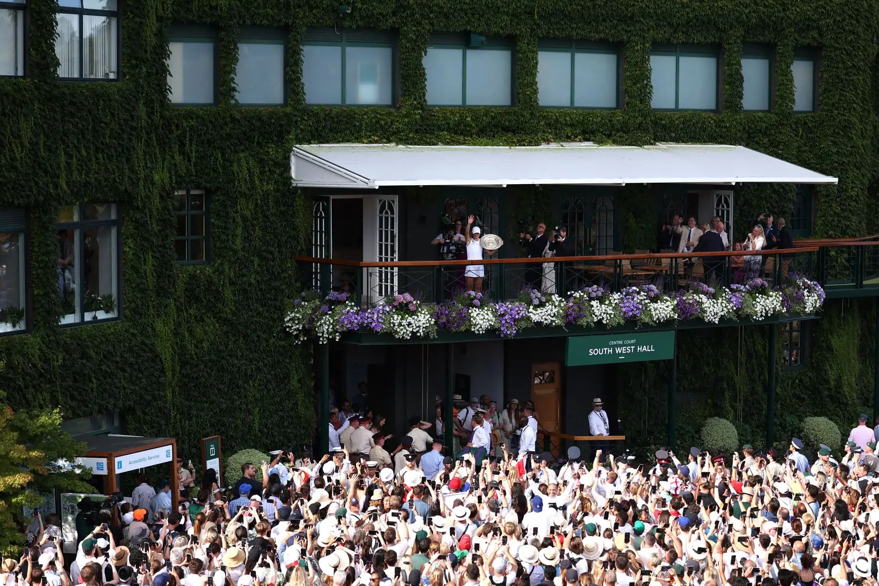 La polaca Iga Swiatek celebra con el trofeo de ganadora, el Venus Rosewater Dish, mientras lo muestra a la multitud desde el balcón de la cancha central después de ganar su partido final de tenis individual femenino contra la jugadora estadounidense Amanda Anisimova en el decimotercer día del Campeonato de Wimbledon 2025. Foto: ANDINA/AFP