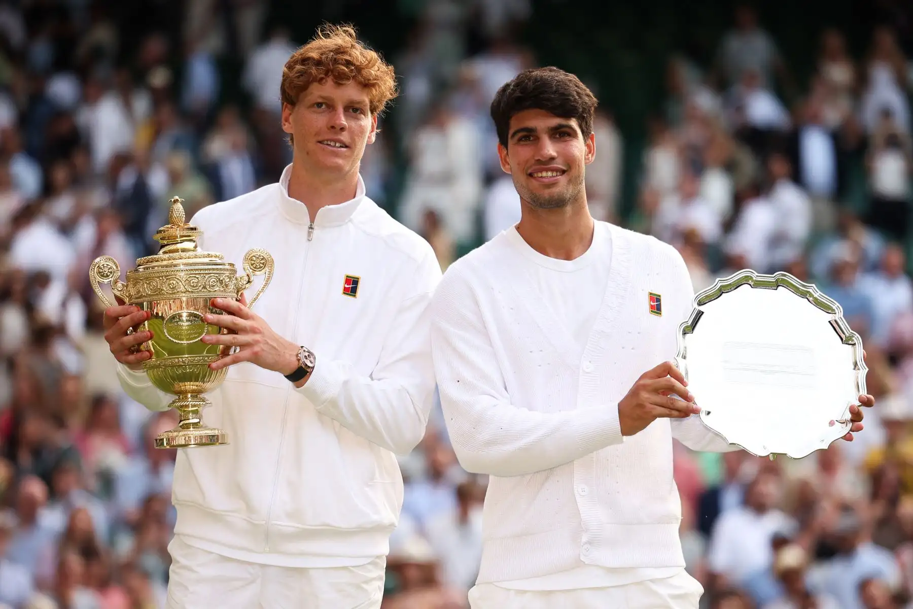 El italiano Jannik Sinner  sostiene el trofeo de ganador y el español Carlos Alcaraz, segundo clasificado, posan para fotos durante la ceremonia de premios al final de su partido final de tenis individual masculino en el decimocuarto día del Campeonato de Wimbledon 2025 en el All England Lawn Tennis and Croquet Club en Wimbledon, al suroeste de Londres. Foto: ANDINA/AFP