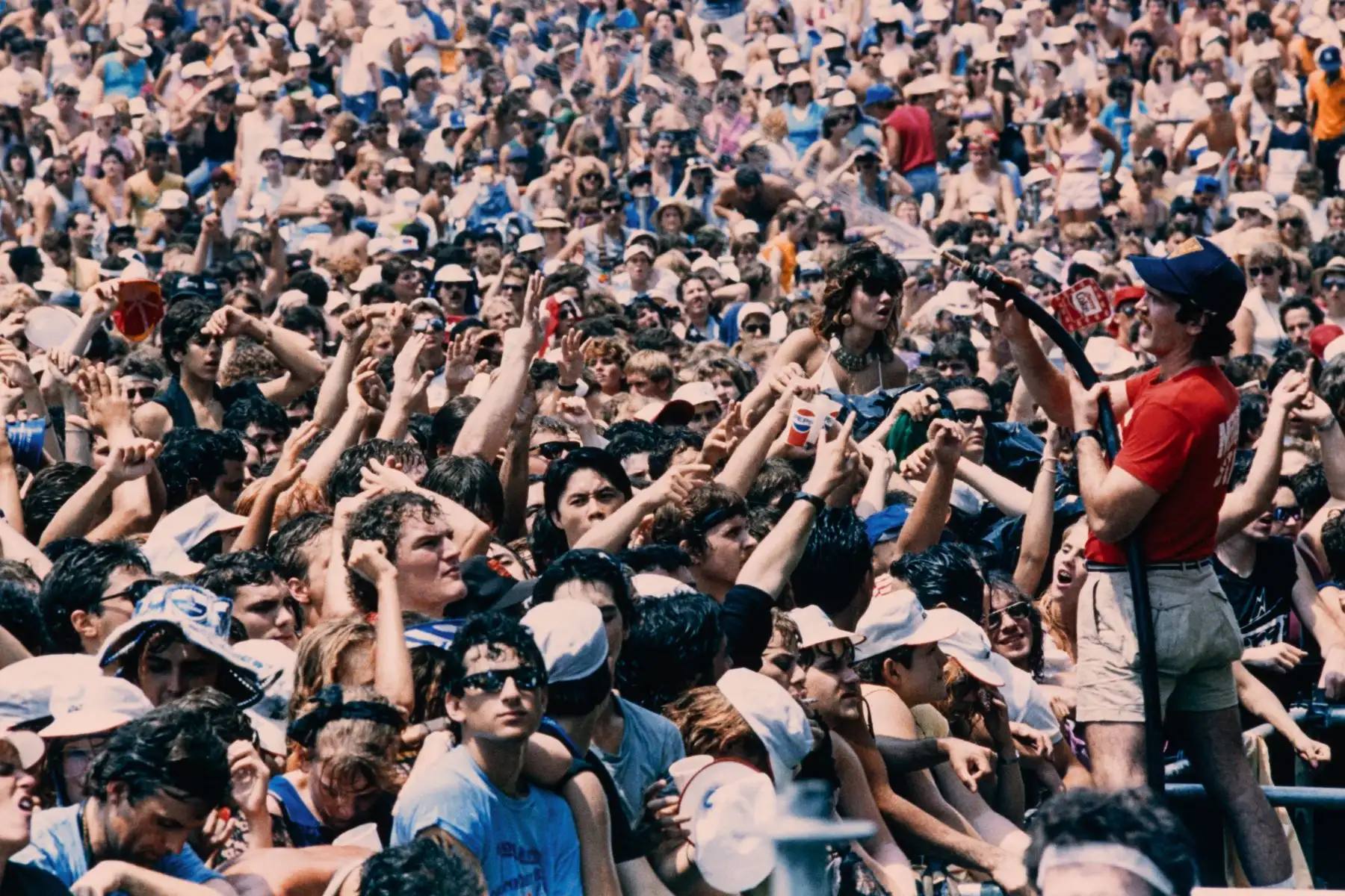 Un miembro del personal rocía agua a los espectadores durante el primer concierto Live Aid en el estadio JFK, en Filadelfia, el 13 de julio de 1985. 
Foto: AFP