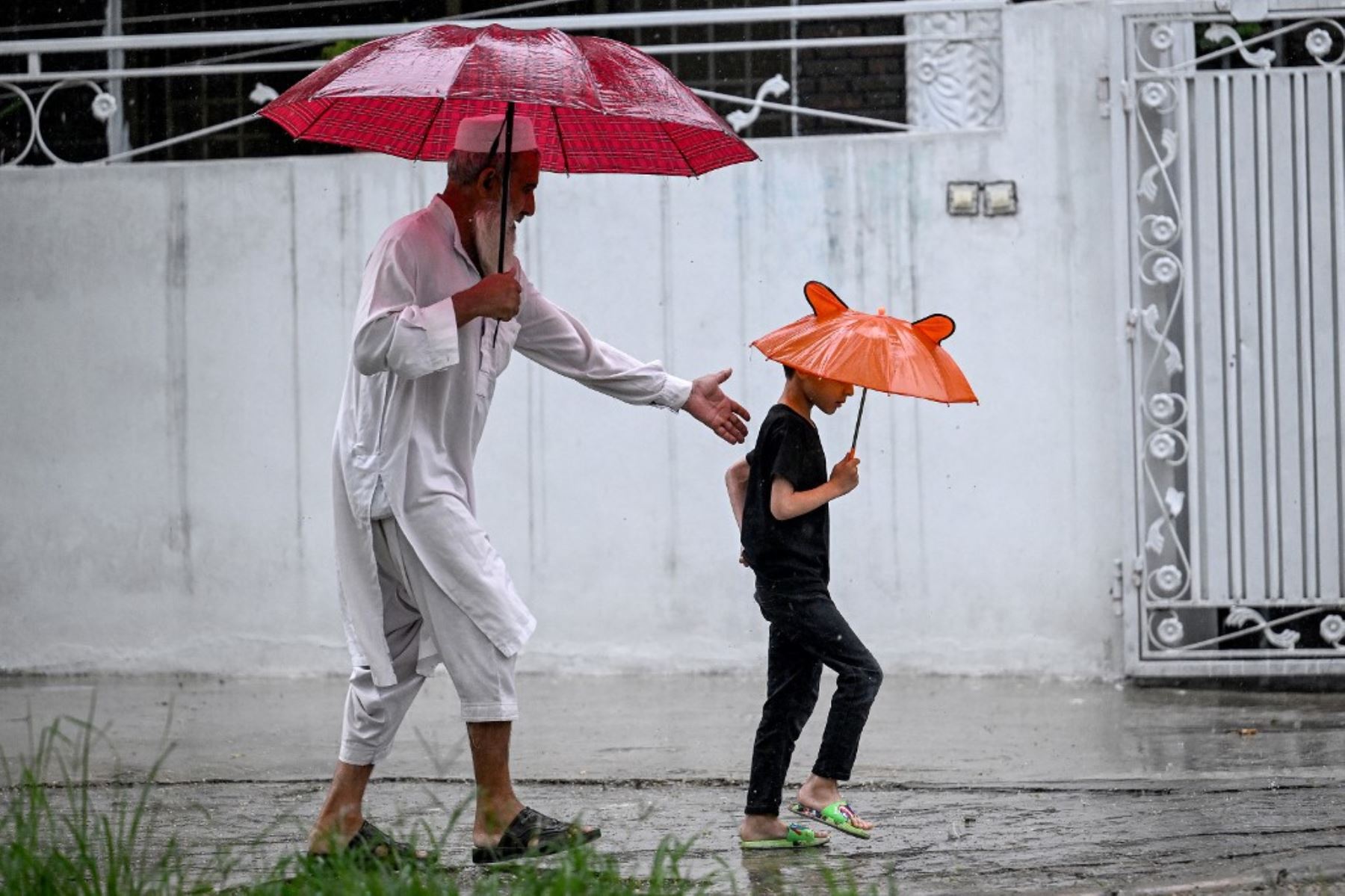 Un hombre y un niño con paraguas caminan por una calle durante las lluvias monzónicas en Islamabad el. Las lluvias monzónicas en Pakistán se han relacionado con más de 110 muertes, incluidas docenas de niños, desde que llegaron a fines de junio, según cifras del gobierno publicadas. AFP