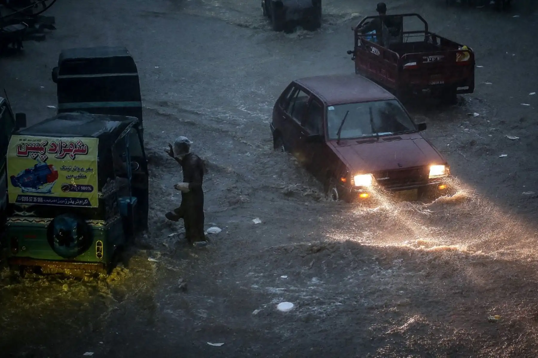 Los viajeros se abren paso por una carretera inundada durante las fuertes lluvias monzónicas en Hyderabad, provincia de Sindh. AFP