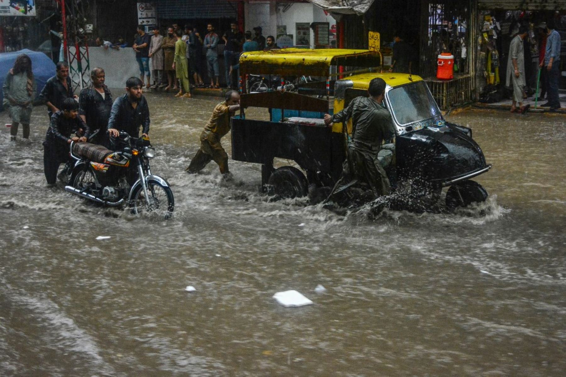 Los viajeros caminan por una calle inundada durante las fuertes lluvias monzónicas en Hyderabad, en la provincia de Sindh. AFP