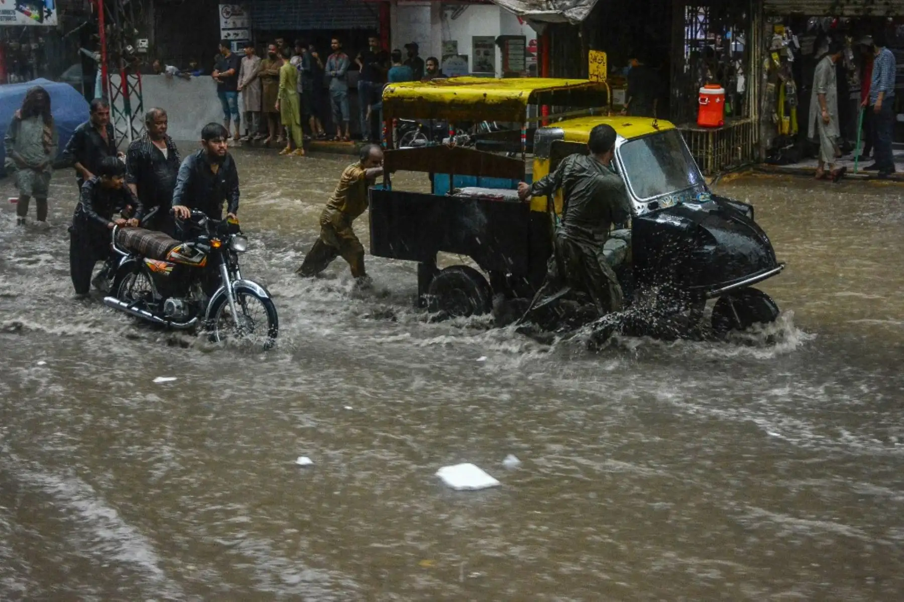 Los viajeros caminan por una calle inundada durante las fuertes lluvias monzónicas en Hyderabad, en la provincia de Sindh. AFP