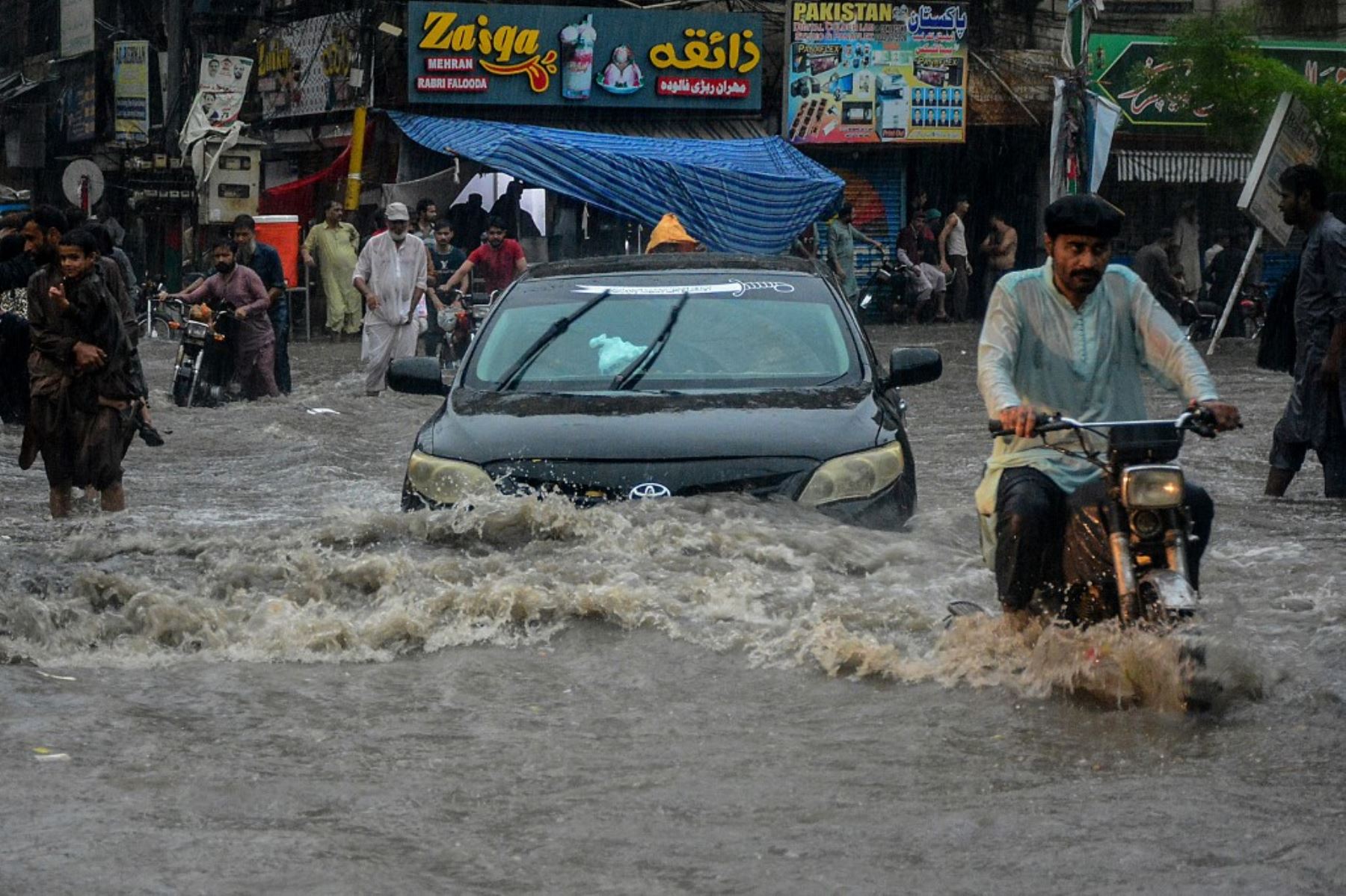 Los viajeros caminan por una calle inundada durante las fuertes lluvias monzónicas en Hyderabad, en la provincia de Sindh. AFP