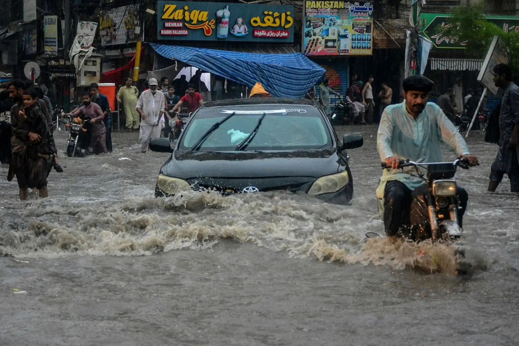 Los viajeros caminan por una calle inundada durante las fuertes lluvias monzónicas en Hyderabad, en la provincia de Sindh. AFP