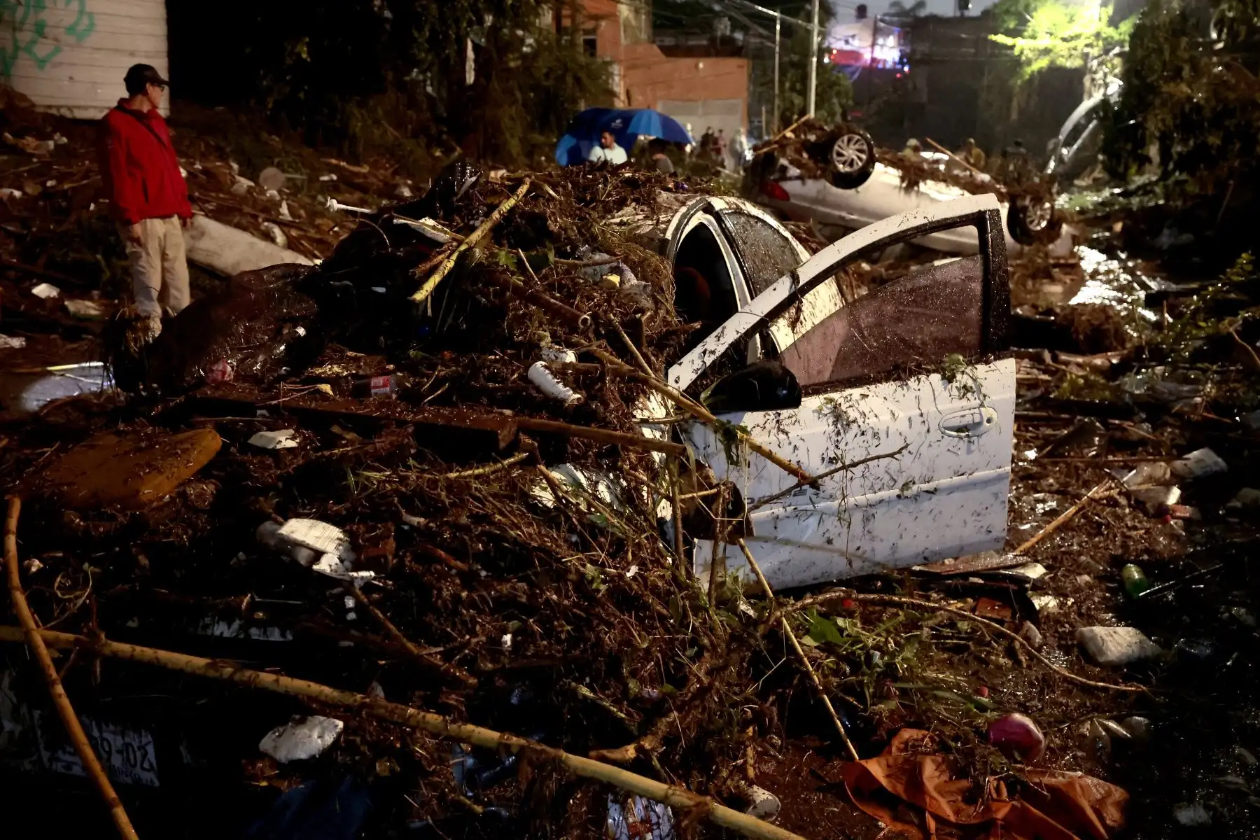 Un hombre se encuentra junto a un automóvil dañado y entre los escombros dejados por las inundaciones repentinas debido a las fuertes lluvias en Zapopan, estado de Jalisco, México. Foto: AFP