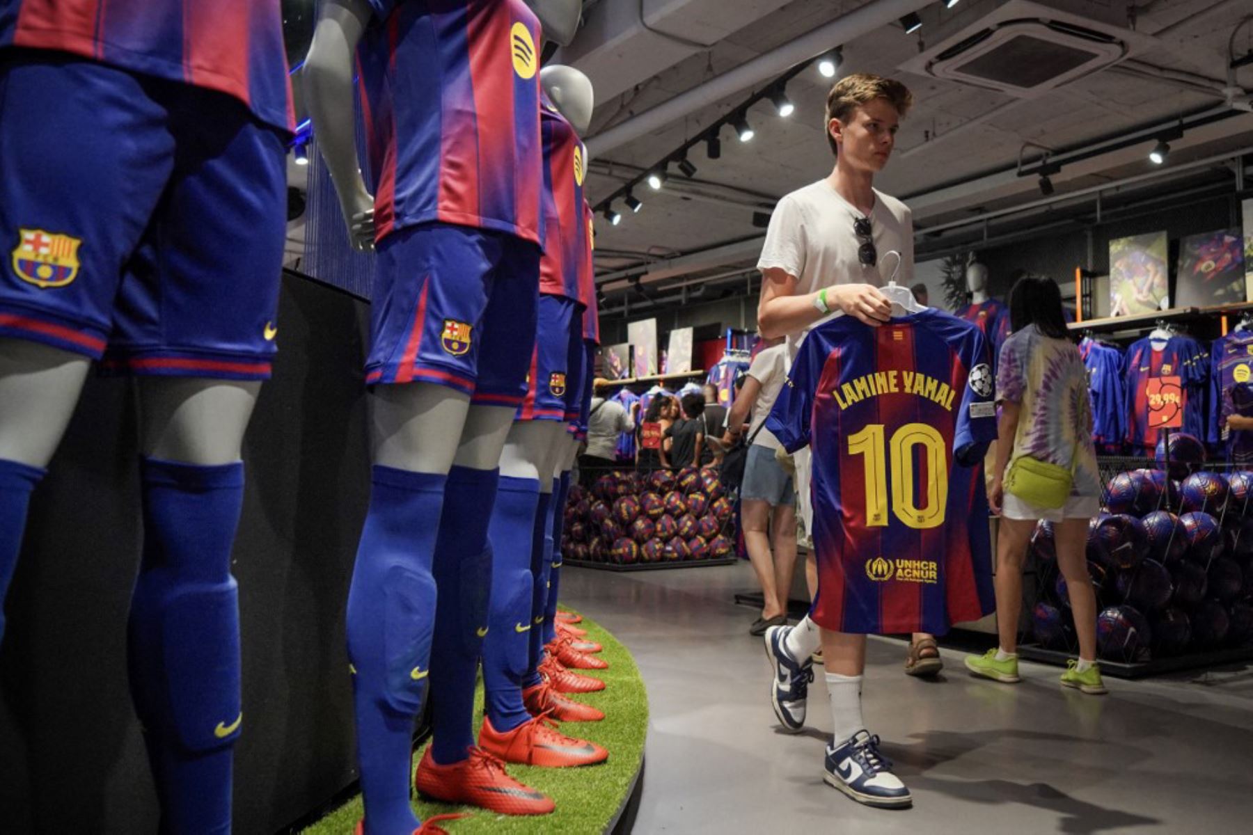 La gente compra la nueva camiseta número 10 del delantero español del Barcelona, Lamine Yamal, en la tienda oficial del FCB en Barcelona. Foto: AFP