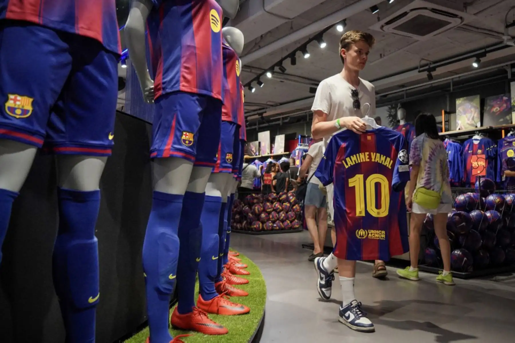 La gente compra la nueva camiseta número 10 del delantero español del Barcelona, Lamine Yamal, en la tienda oficial del FCB en Barcelona. Foto: AFP