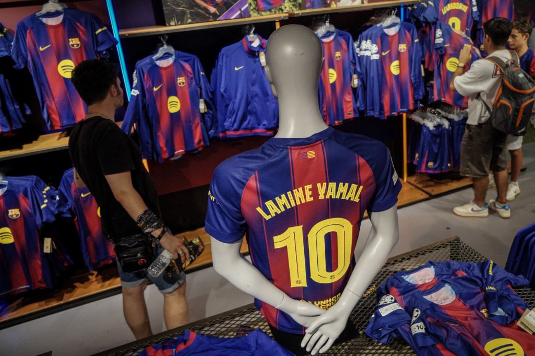 La gente compra la nueva camiseta número 10 del delantero español del Barcelona, Lamine Yamal, en la tienda oficial del FCB en Barcelona. Foto: AFP