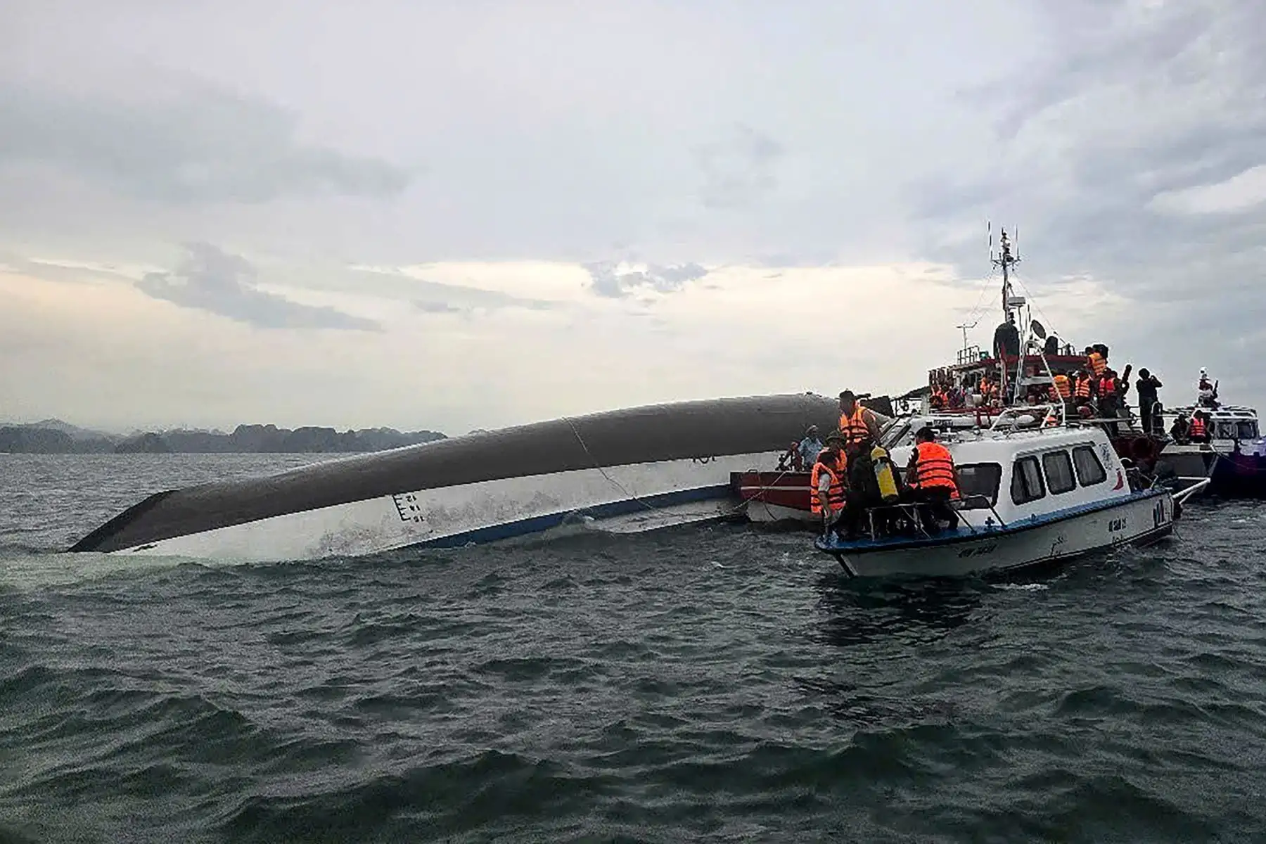 Esta fotografía, tomada el 19 de julio de 2025 y publicada por la Agencia de Noticias de Vietnam , muestra al personal de rescate reunido alrededor de un barco turístico volcado, durante una operación de búsqueda y rescate en la bahía de Ha Long, provincia de Quang Ninh. 
Foto: AFP