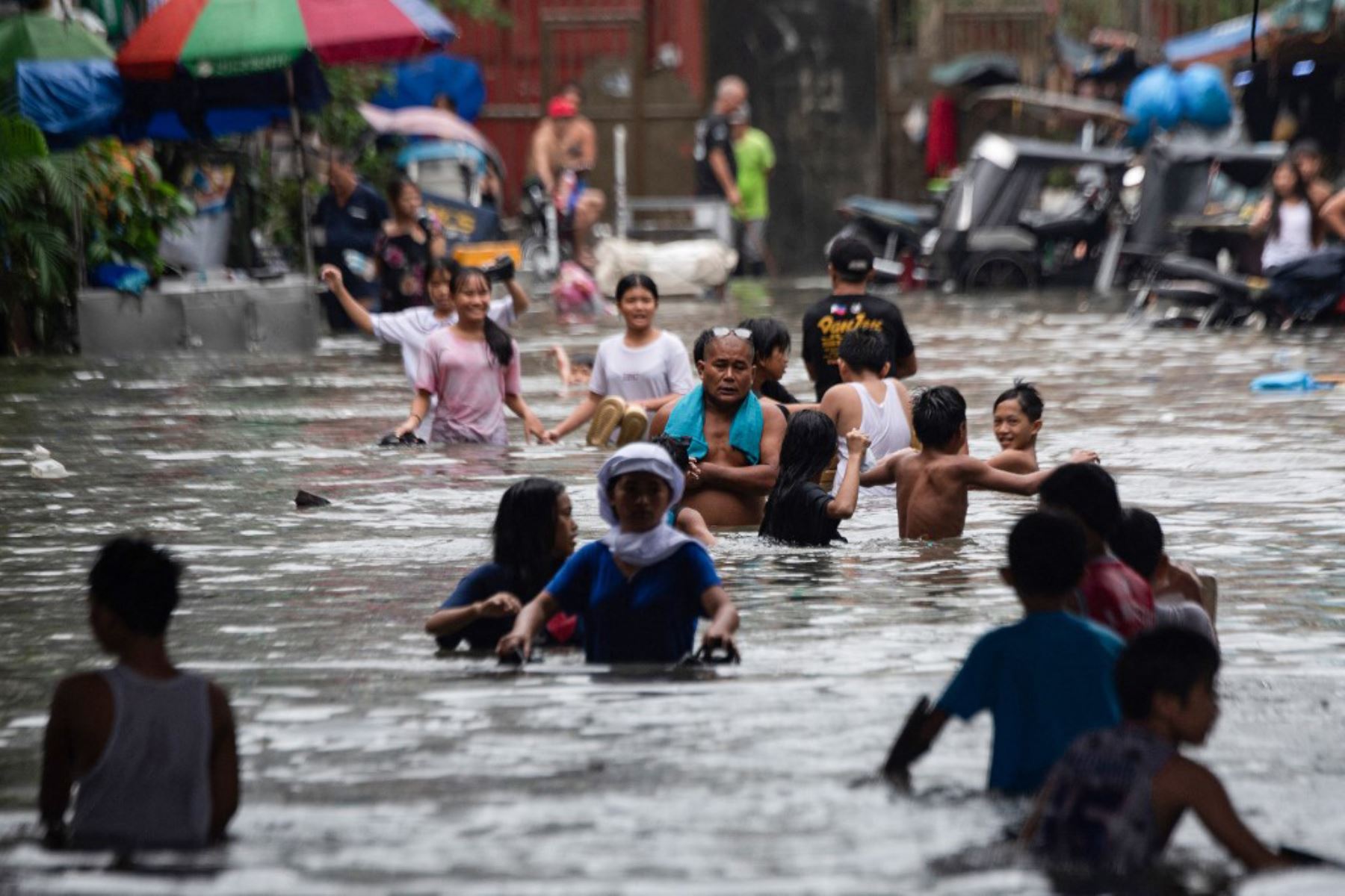Personas cruzan una calle inundada en Manila, después de que el tifón Wipha provocara fuertes lluvias e inundaciones en Filipinas, donde se reportó la desaparición de tres personas, según el Consejo Nacional para la Reducción y Gestión del Riesgo de Desastres. Foto: AFP