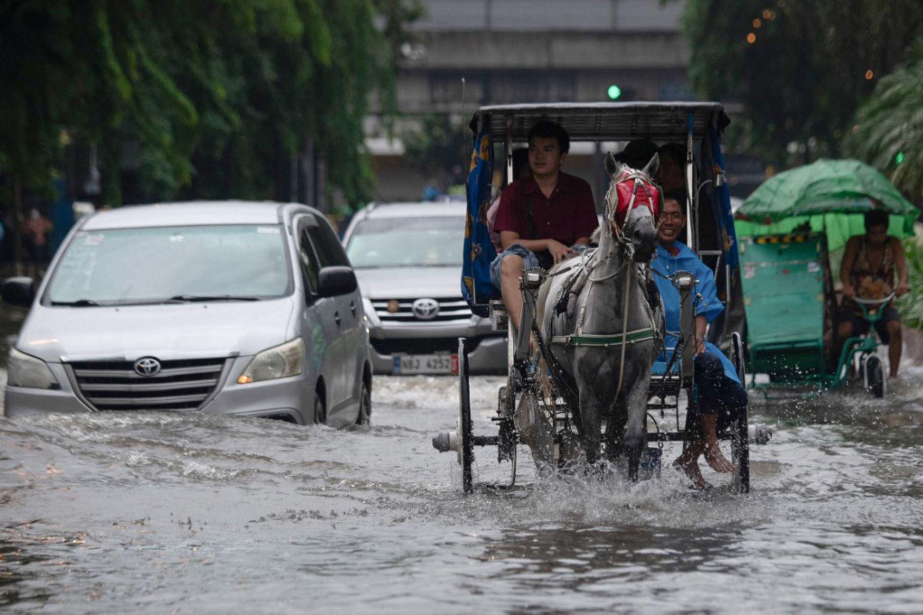 Personas cruzan una calle inundada en Manila, después de que el tifón Wipha provocara fuertes lluvias e inundaciones en Filipinas, donde se reportó la desaparición de tres personas, según el Consejo Nacional para la Reducción y Gestión del Riesgo de Desastres. Foto: AFP