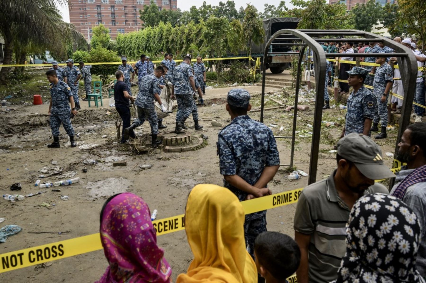 Los espectadores se reúnen mientras el personal de la Fuerza Aérea de Bangladesh recupera escombros mientras inspecciona el lugar del accidente, un día después de que un avión de entrenamiento se estrellara contra una escuela en Dhaka. AFP